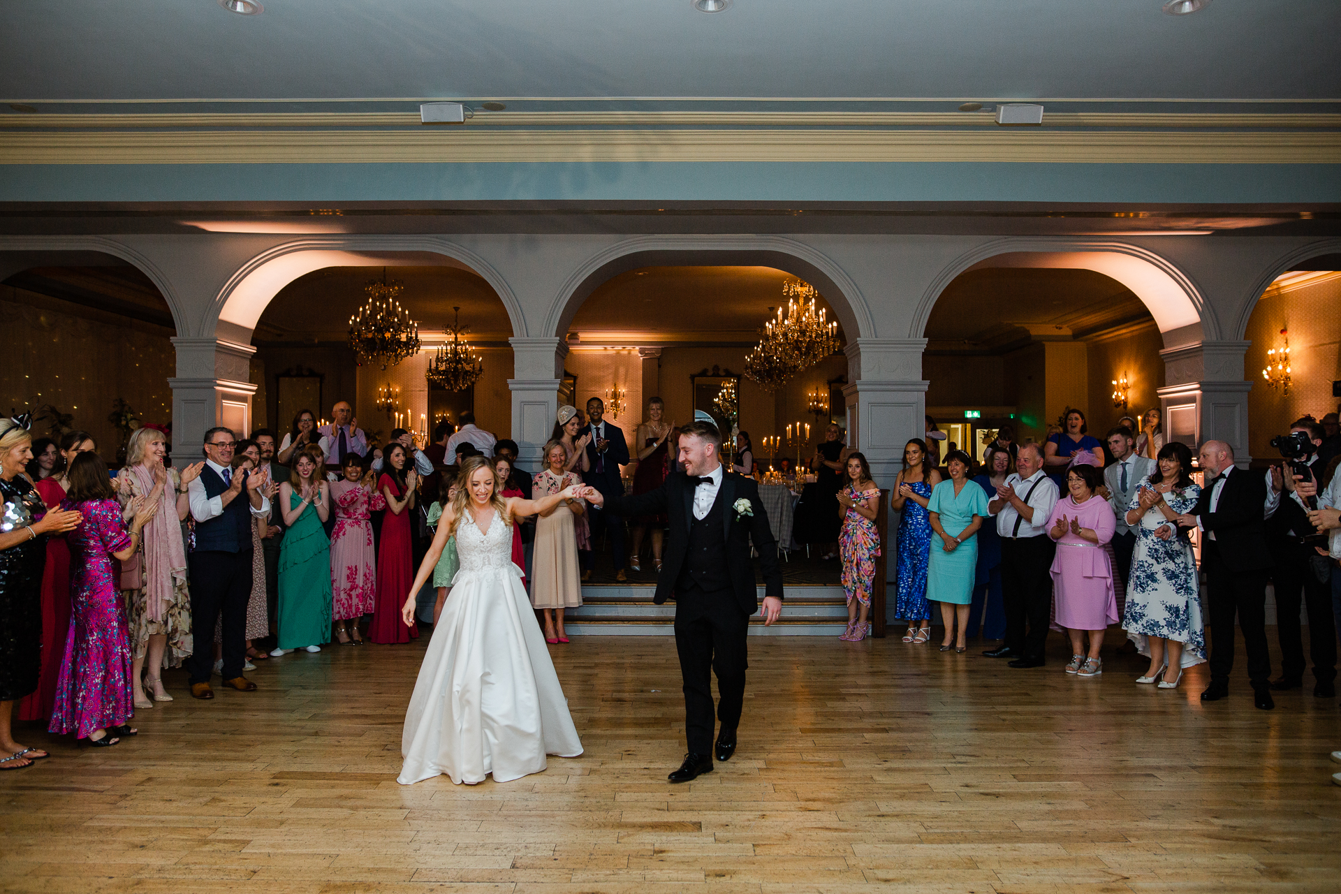 A man and woman walking down a hall with a crowd of people