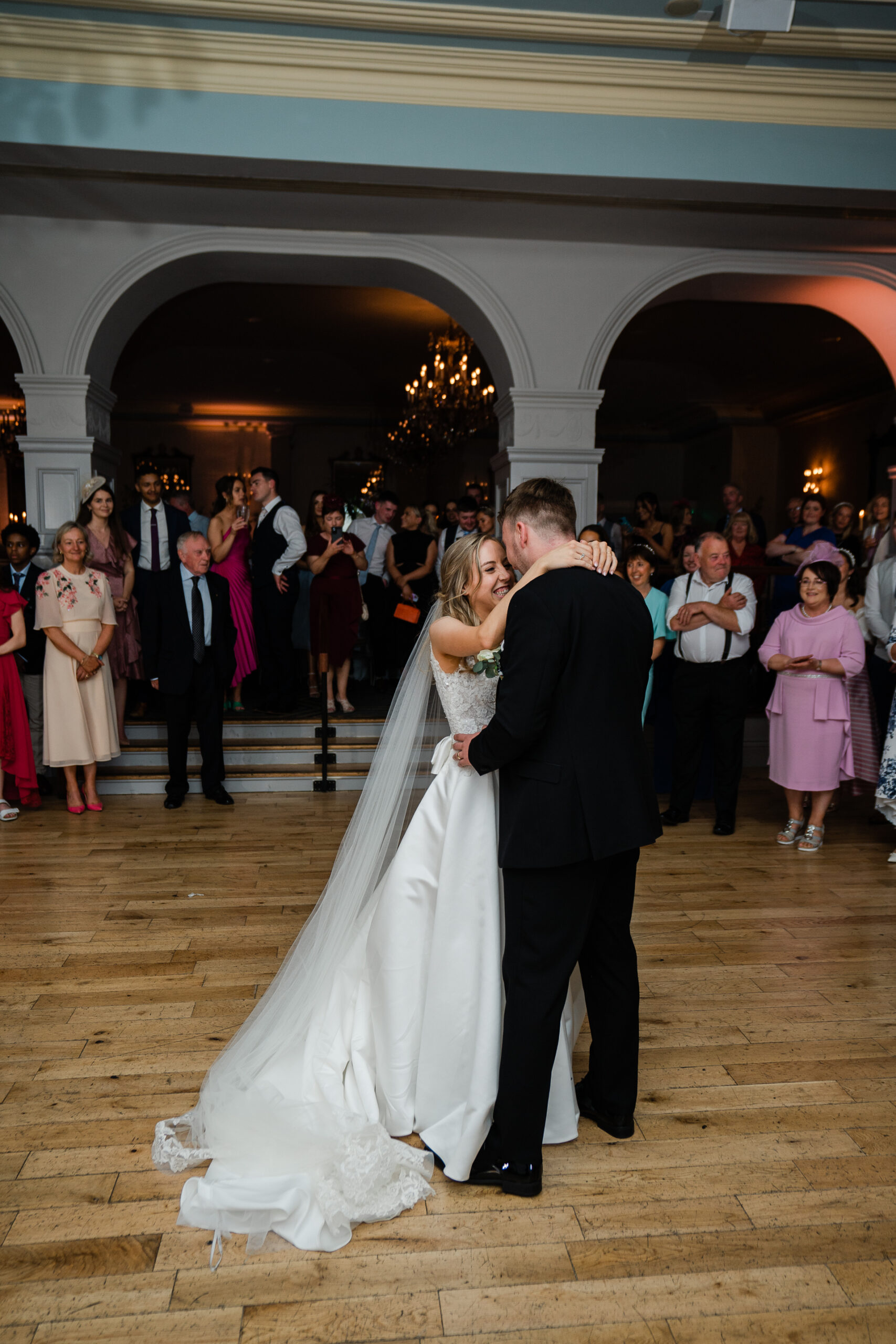 A man and woman kissing in a large room with a large group of people