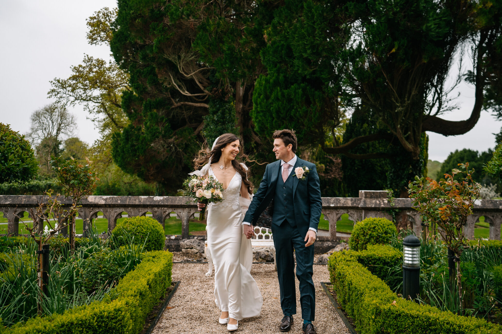 A man and woman walking down a path in a garden