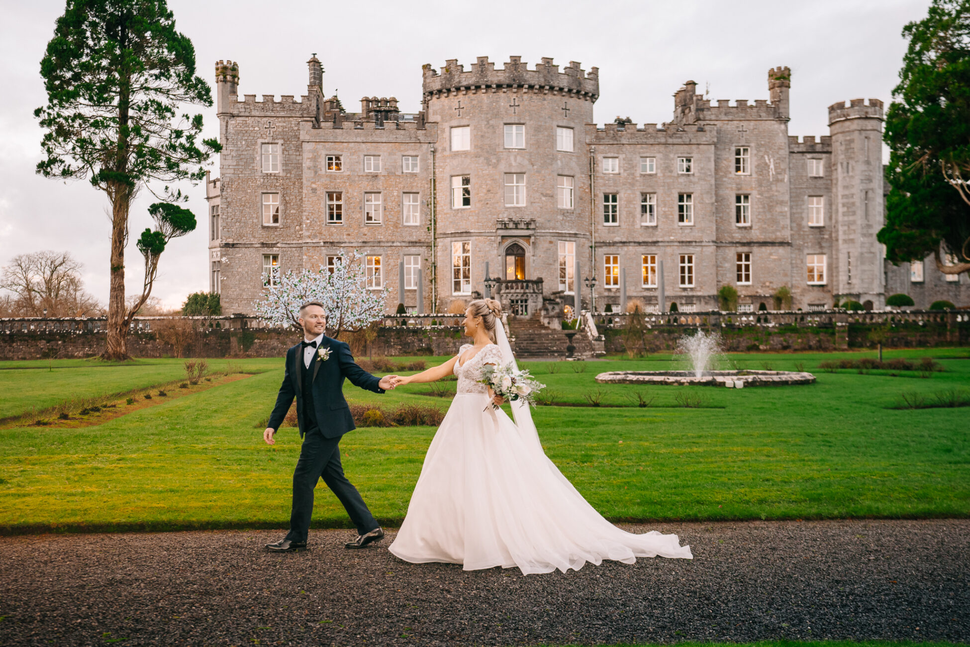 A man and woman in wedding attire walking in front of a large building