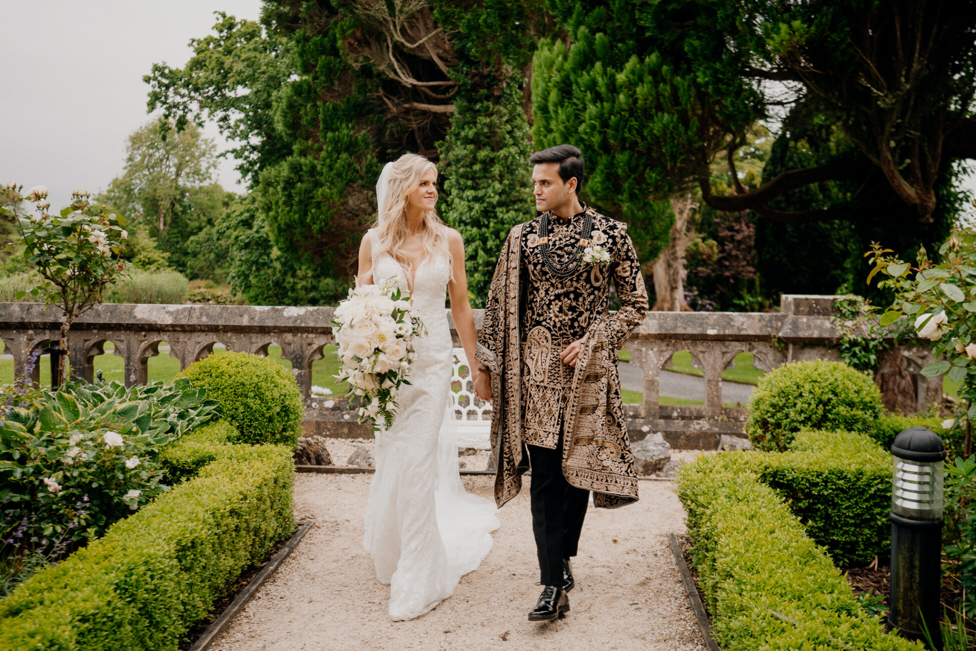 A man and woman walking down a path with flowers and trees