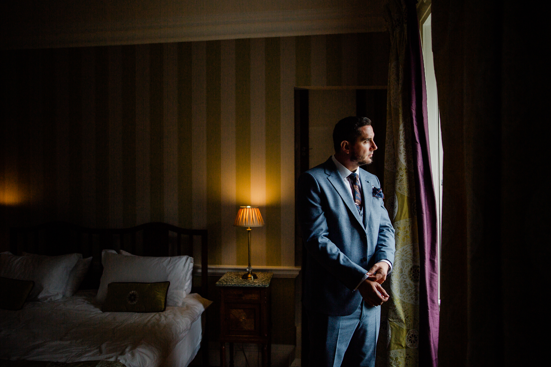 A person in a suit stands in a bedroom