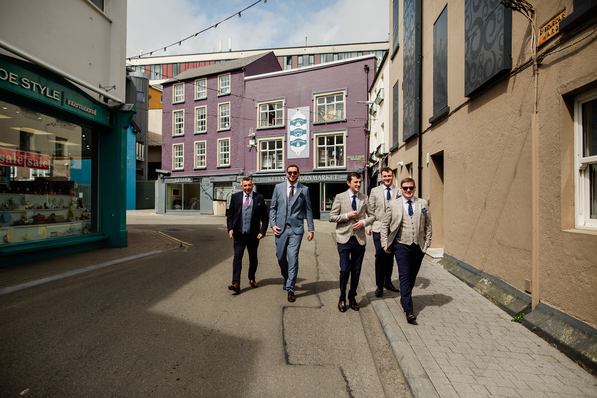 A group of people walking down a street between buildings