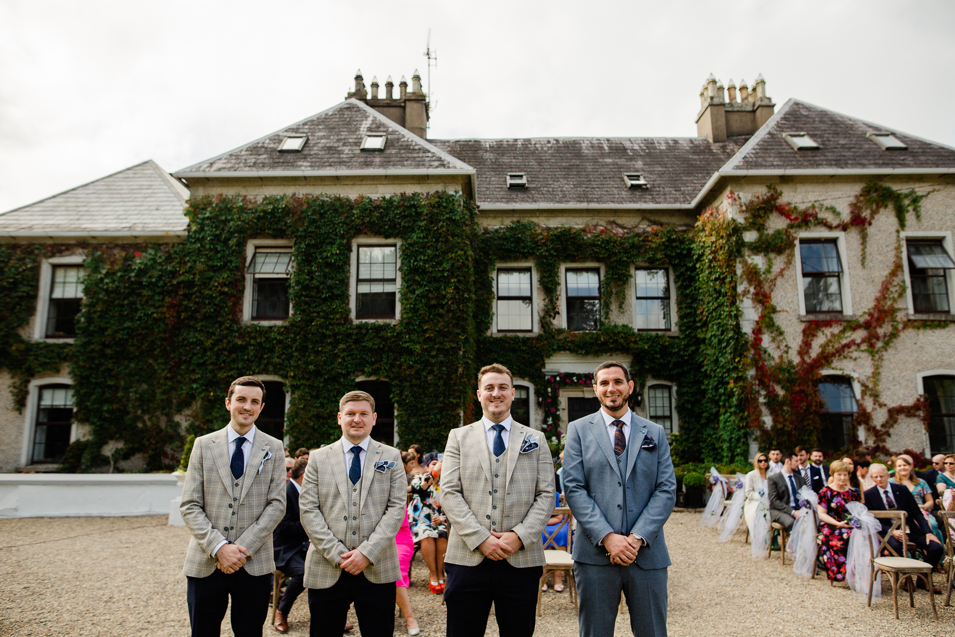 A group of men posing for a picture in front of a large building