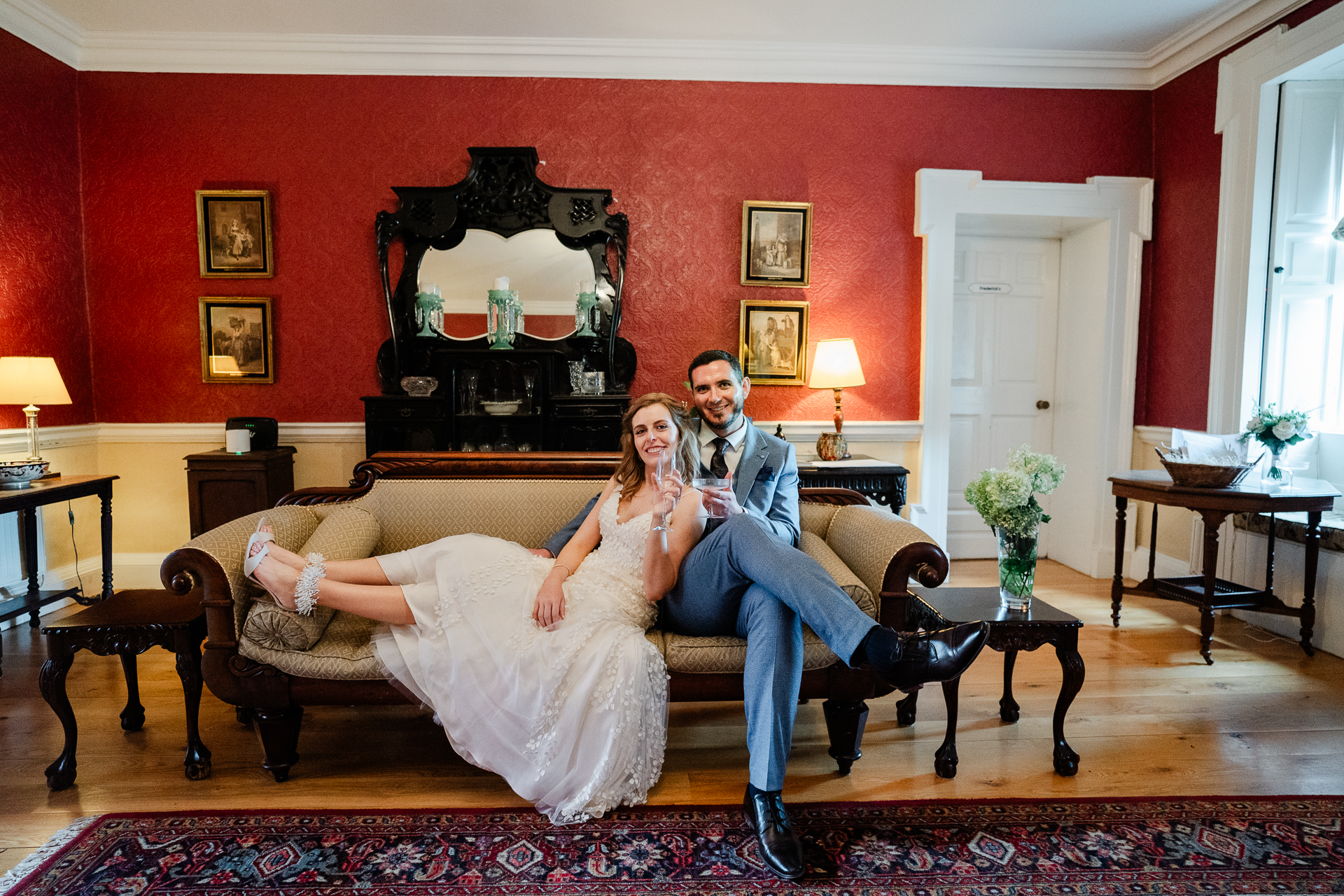 A man and woman sitting on a couch in a room with red walls