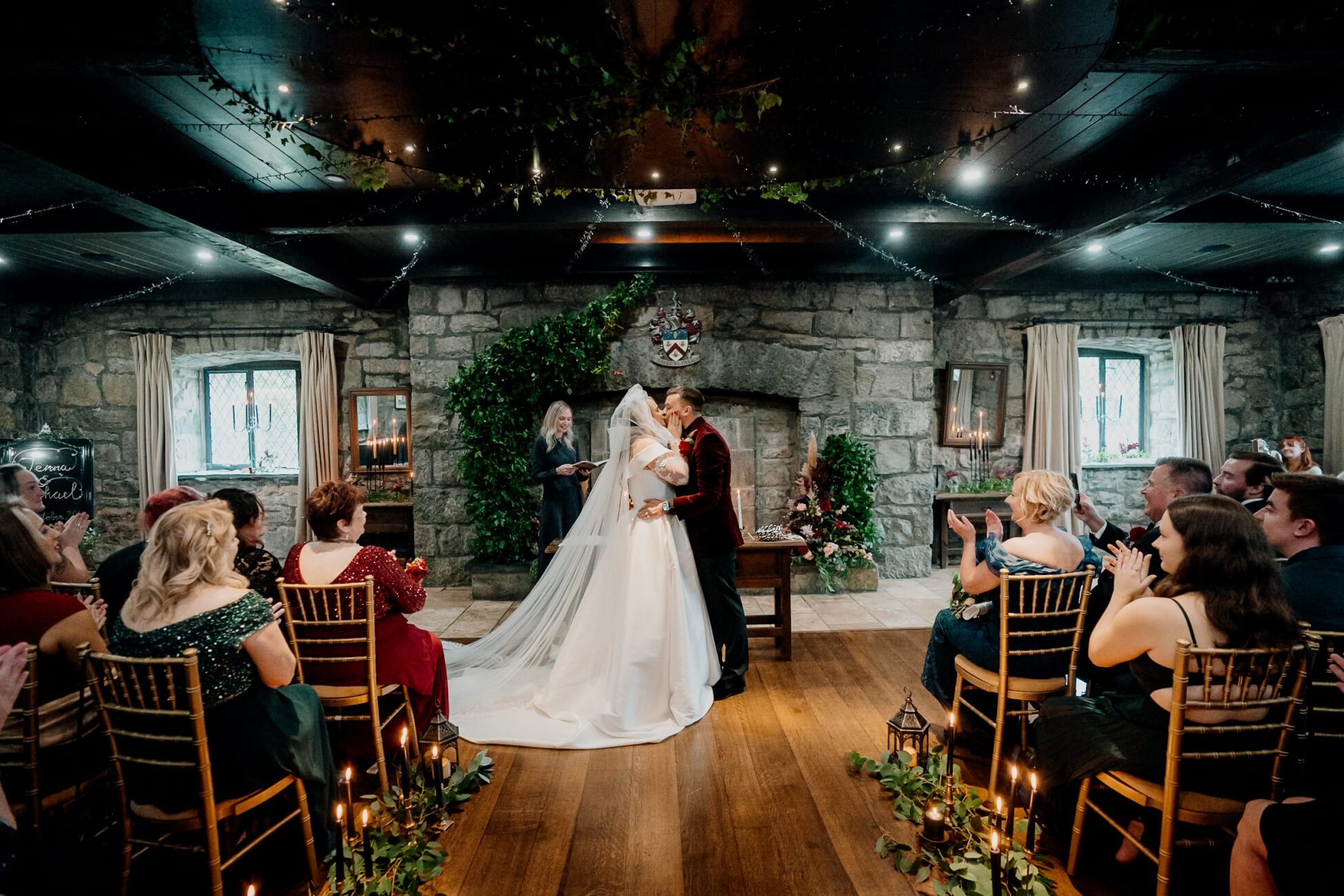 A man and woman kissing in a room with people sitting in chairs