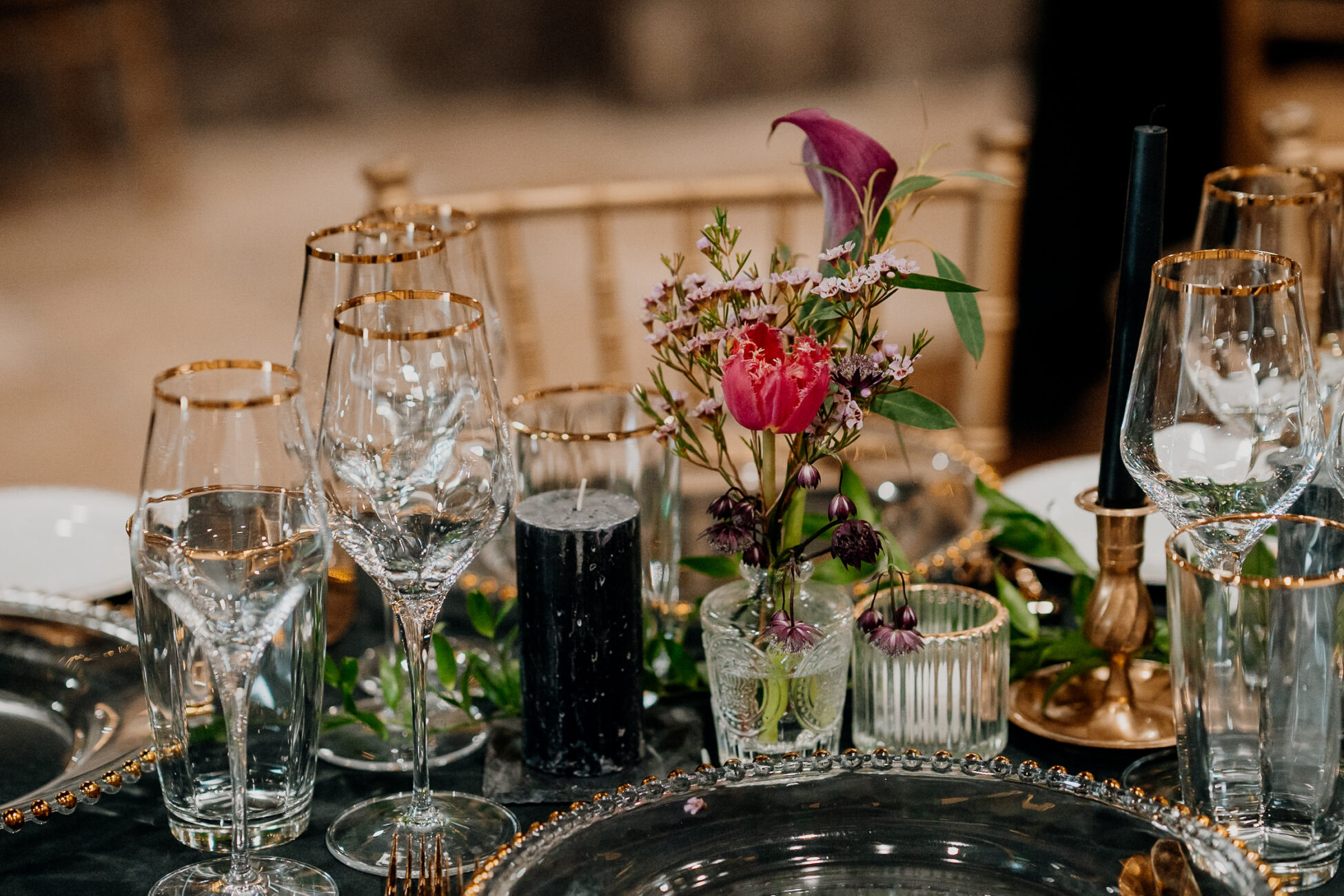 A vase with flowers and glasses on a table