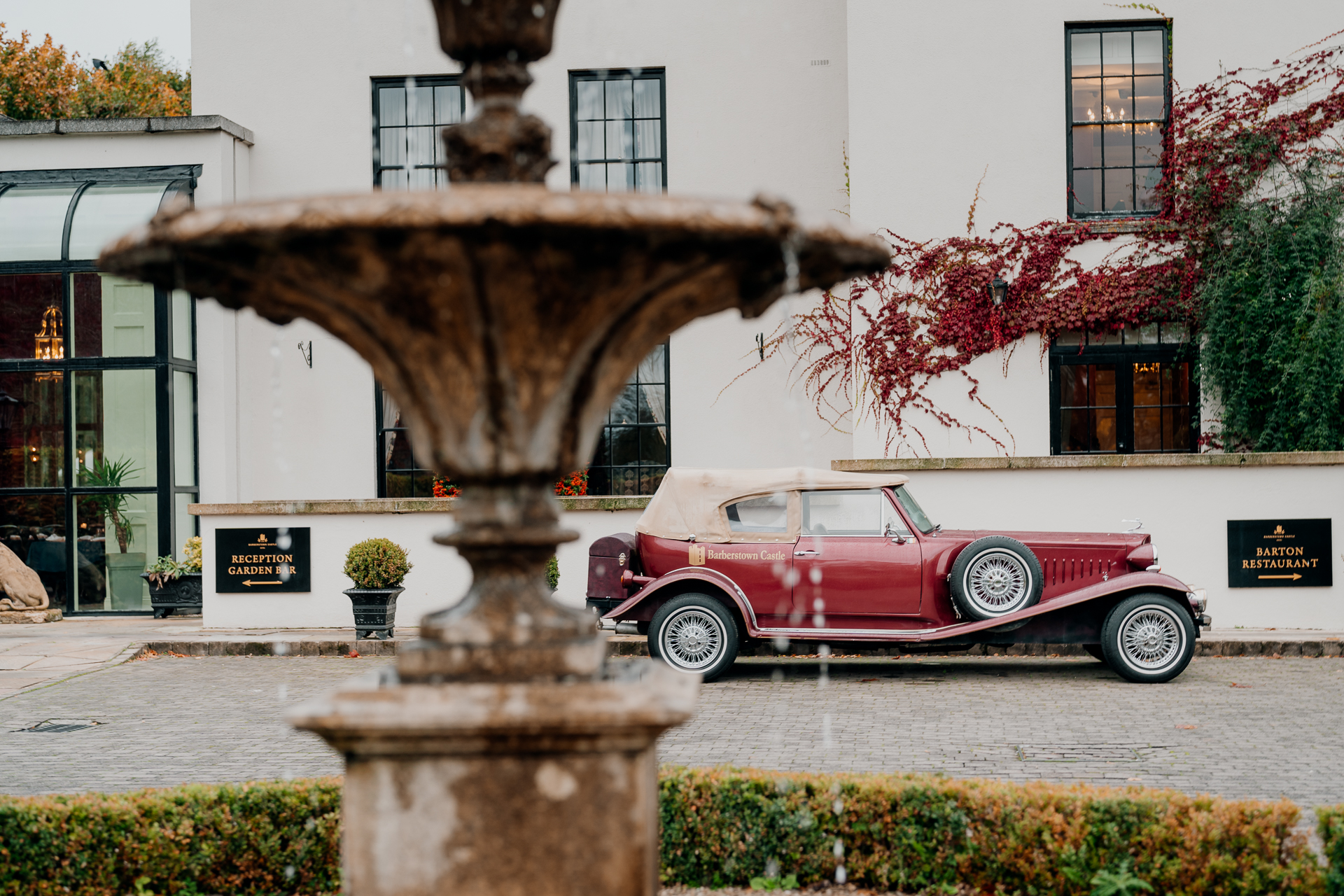 A red car parked in front of a fountain