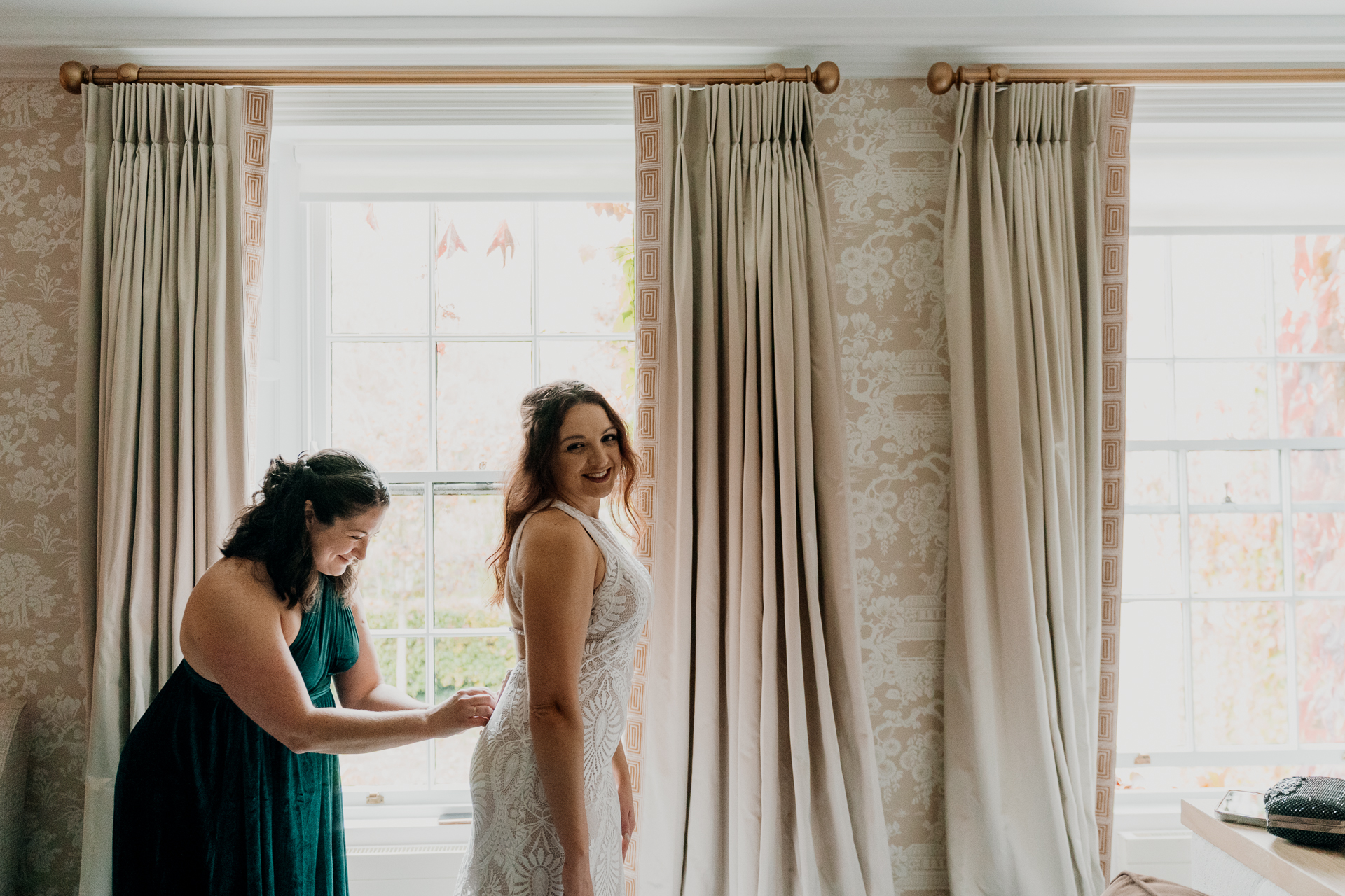 A person in a dress and a person in a dress in a room with curtains