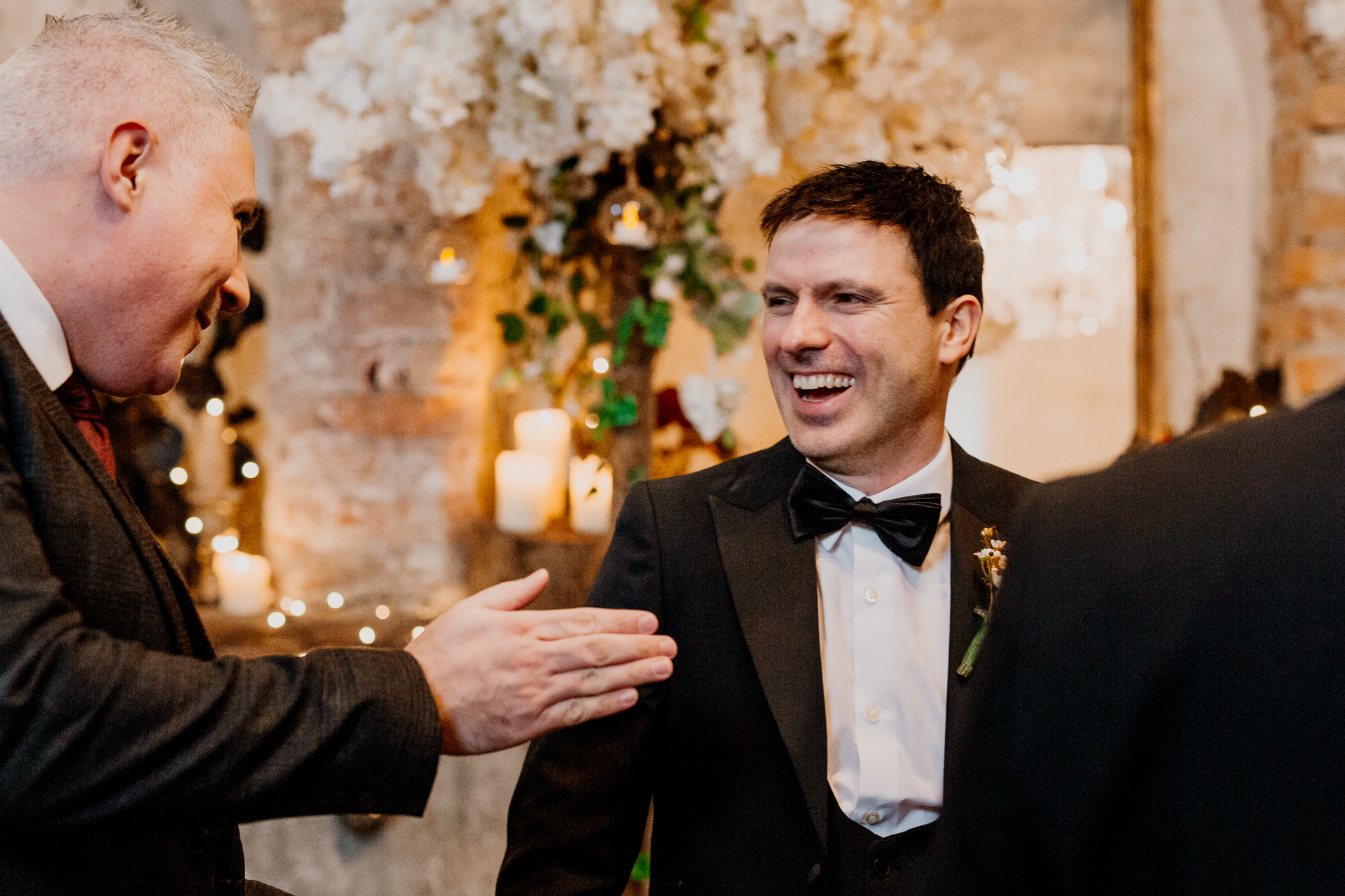 A man in a tuxedo talking to another man in a tuxedo