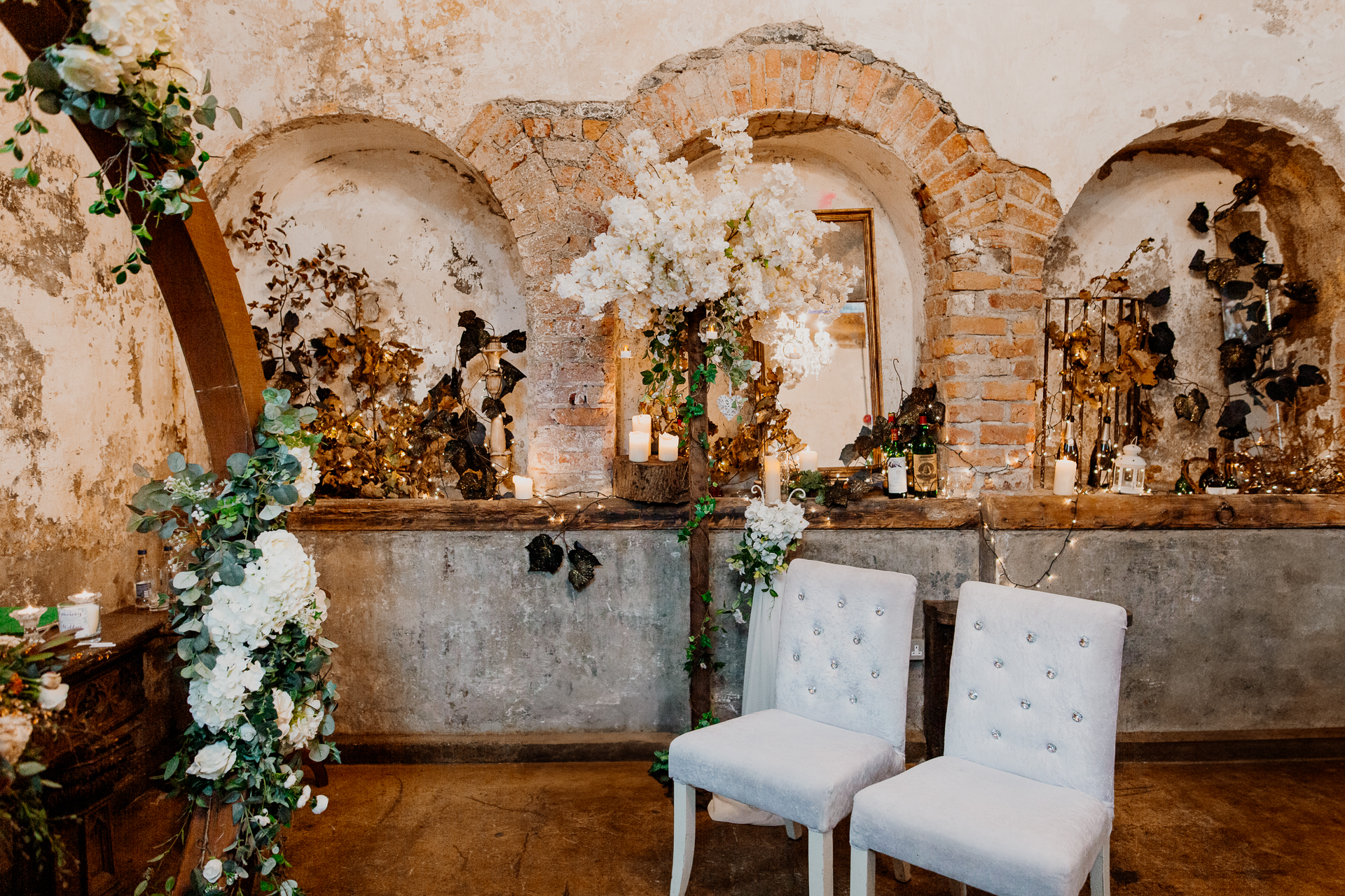 A room with white chairs and a stone wall with flowers