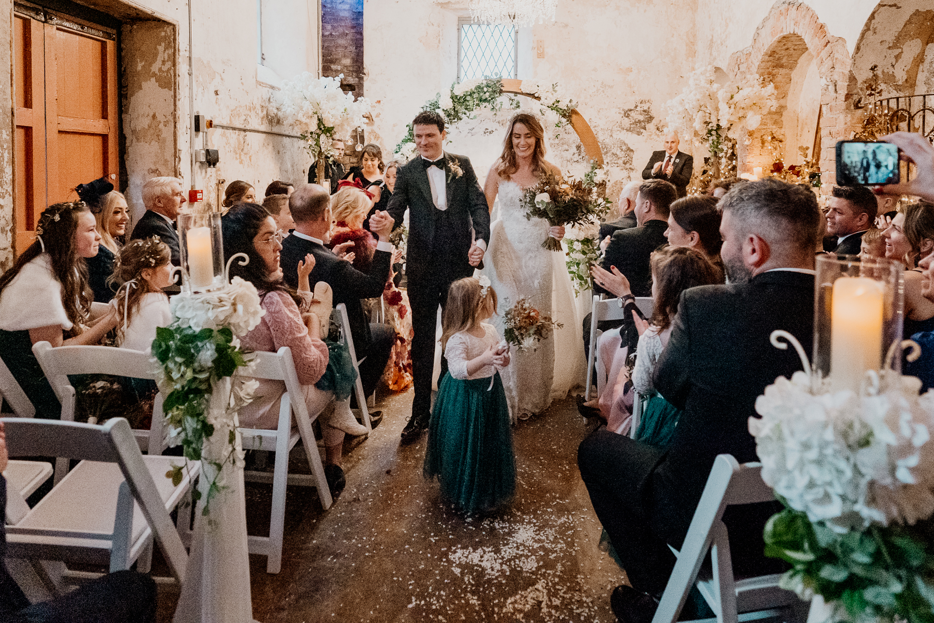 A man and woman walking down a aisle with a woman in a dress