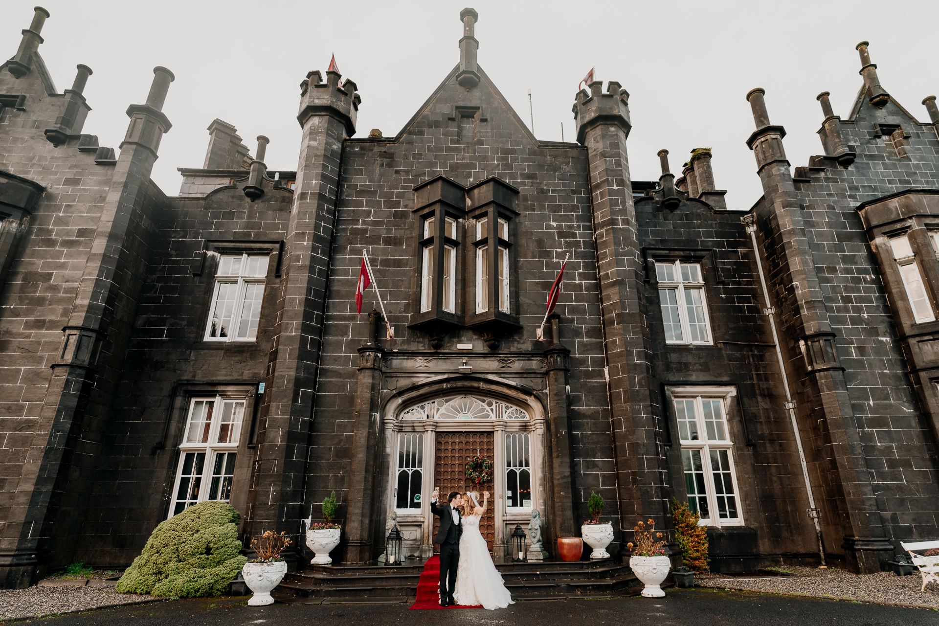 A couple in wedding attire outside a large brick building