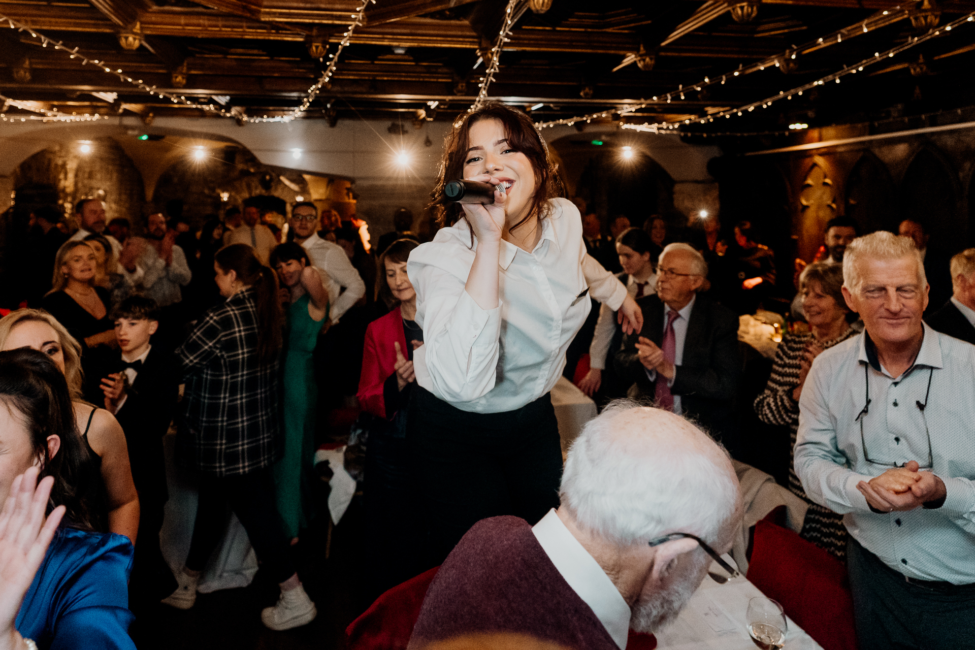 A person singing into a microphone in a crowded room