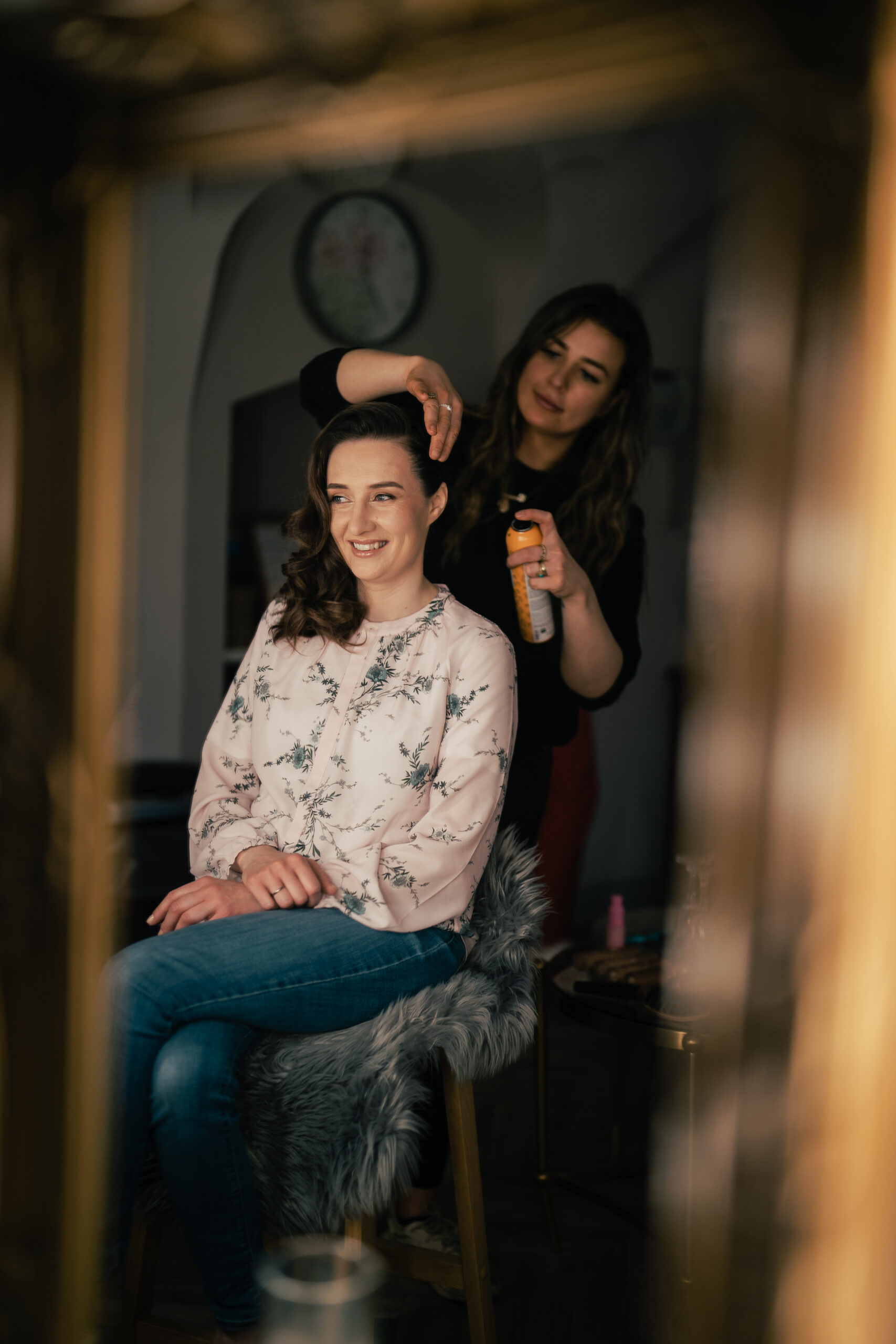 A woman sitting on a chair next to a woman with her hair in the air