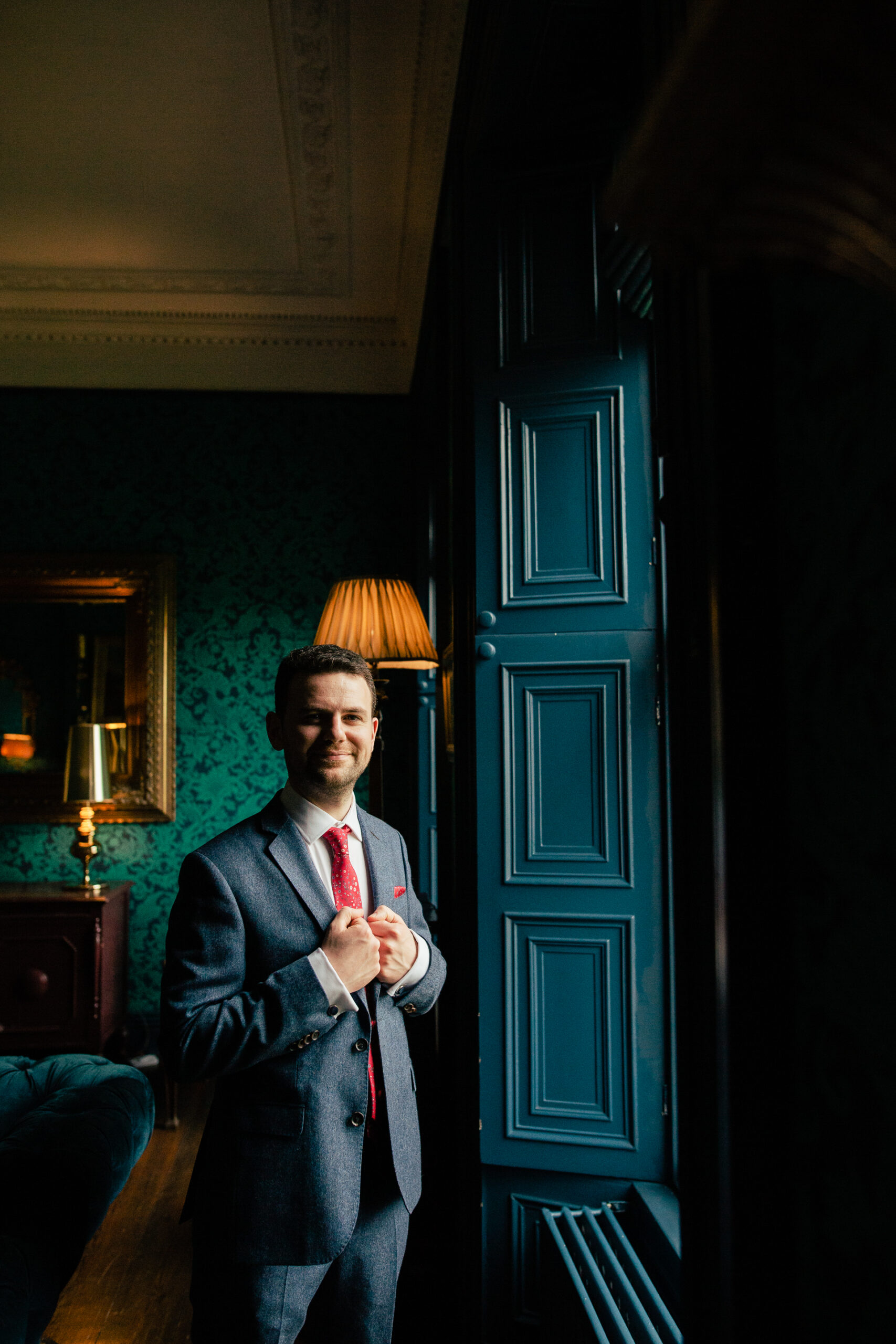 A person in a suit standing in front of a blue door