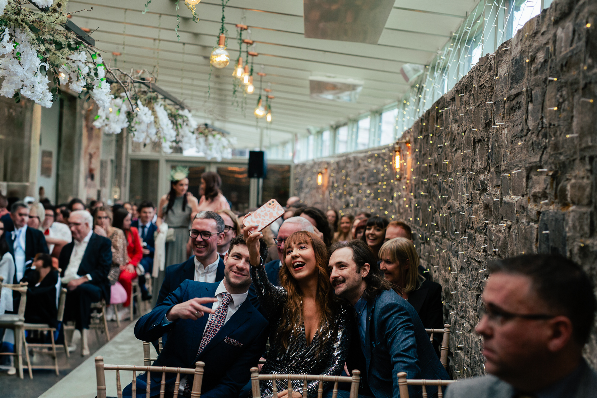 A group of people sitting in a room with a stone wall