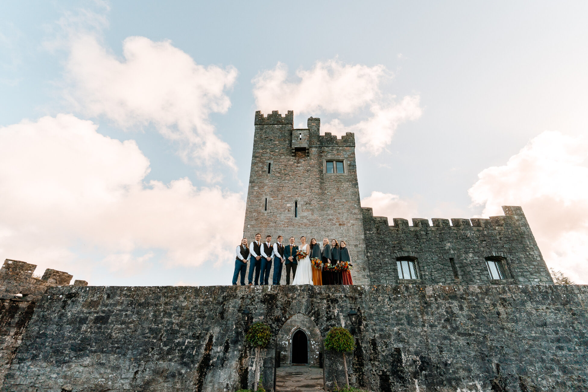 A group of people standing on a stone wall in front of a castle