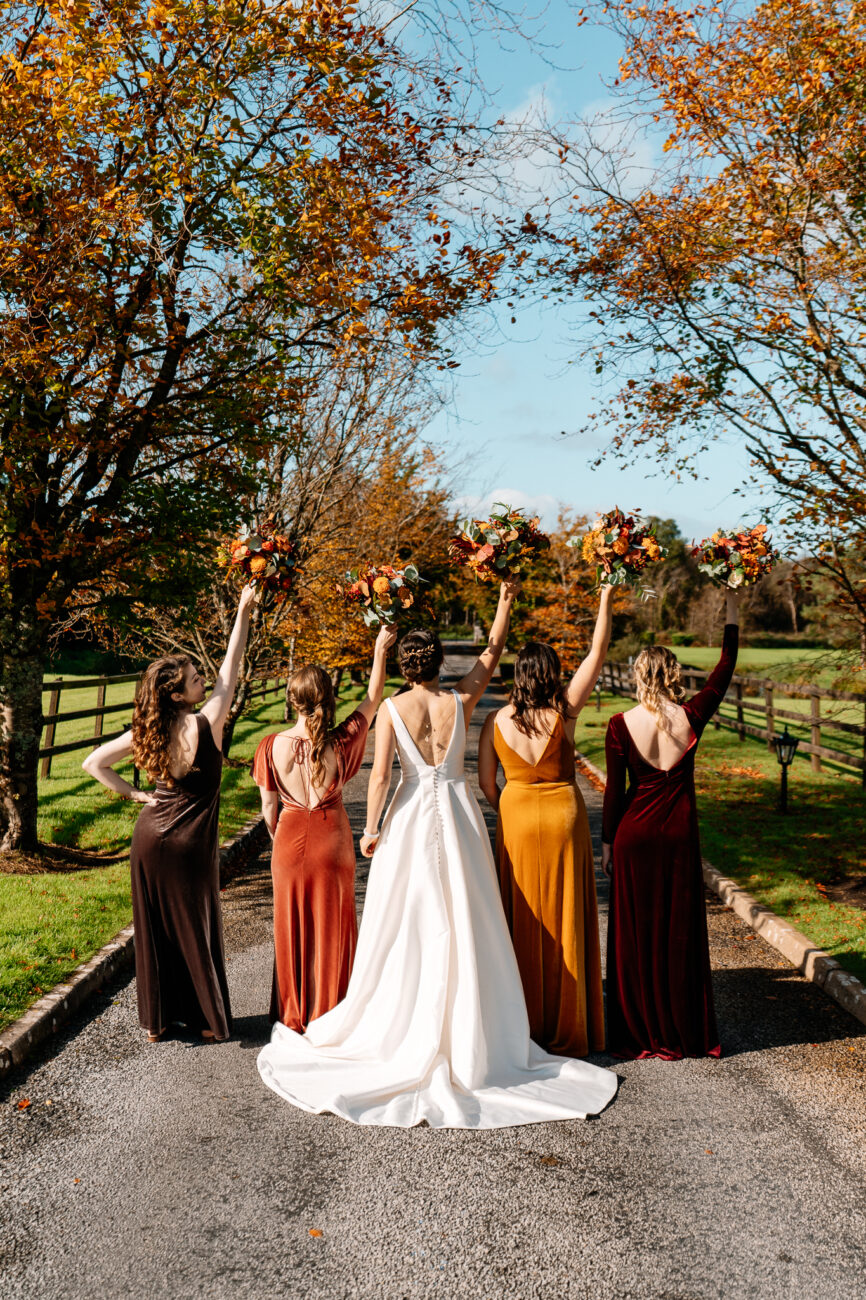 A group of women in dresses and dresses standing on a path with trees