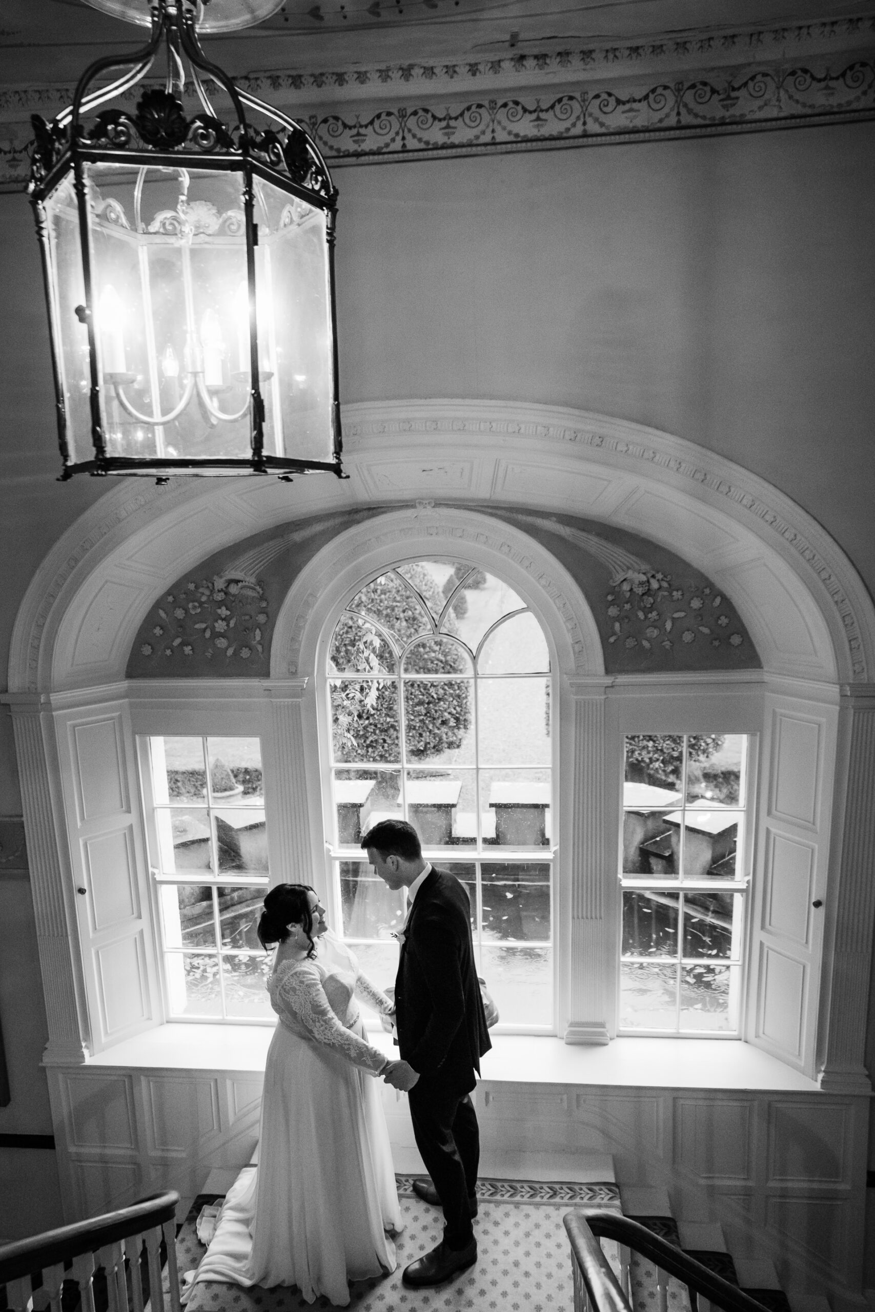 A bride and groom kissing in a room with a chandelier