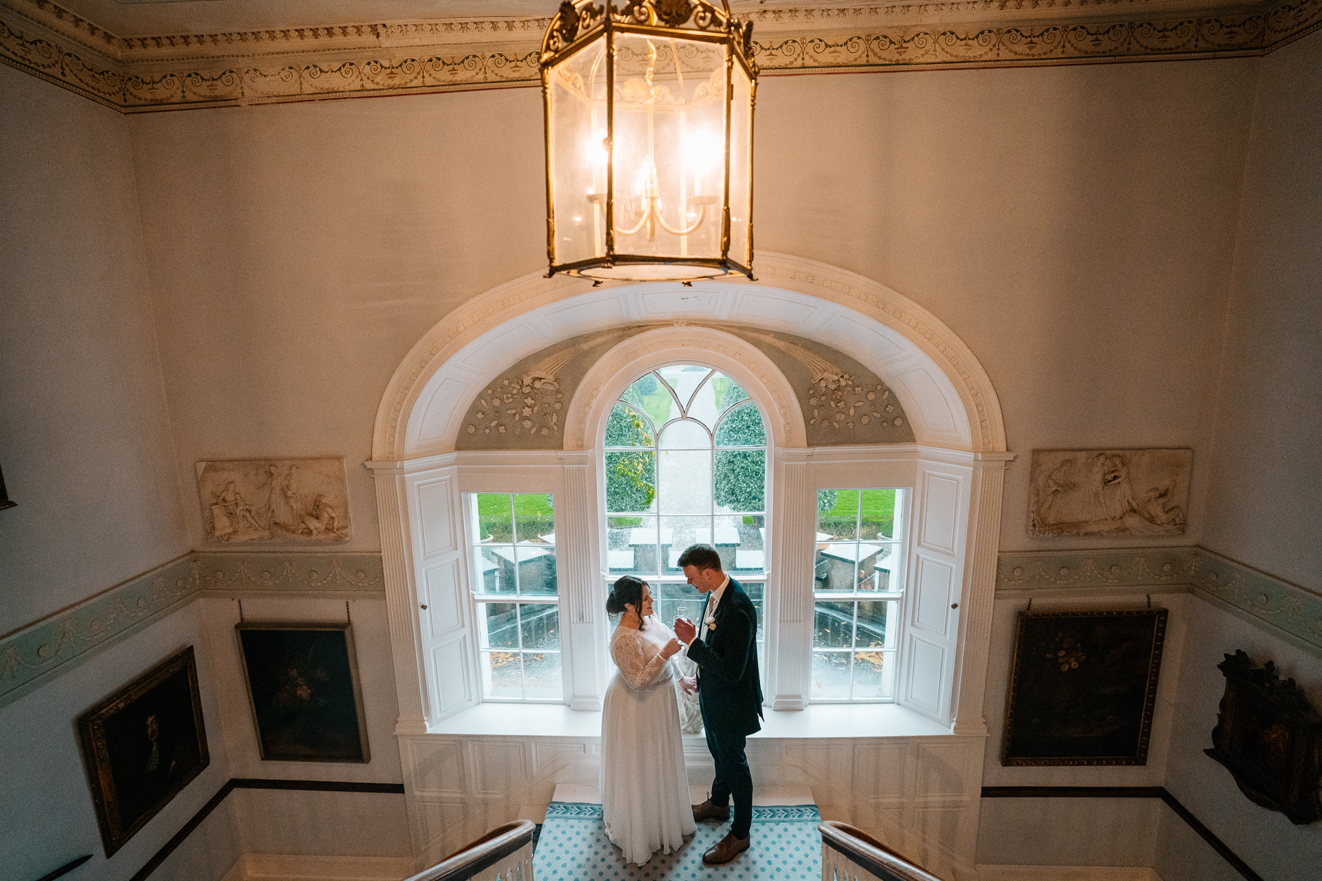 A man and woman kissing in a room with a chandelier