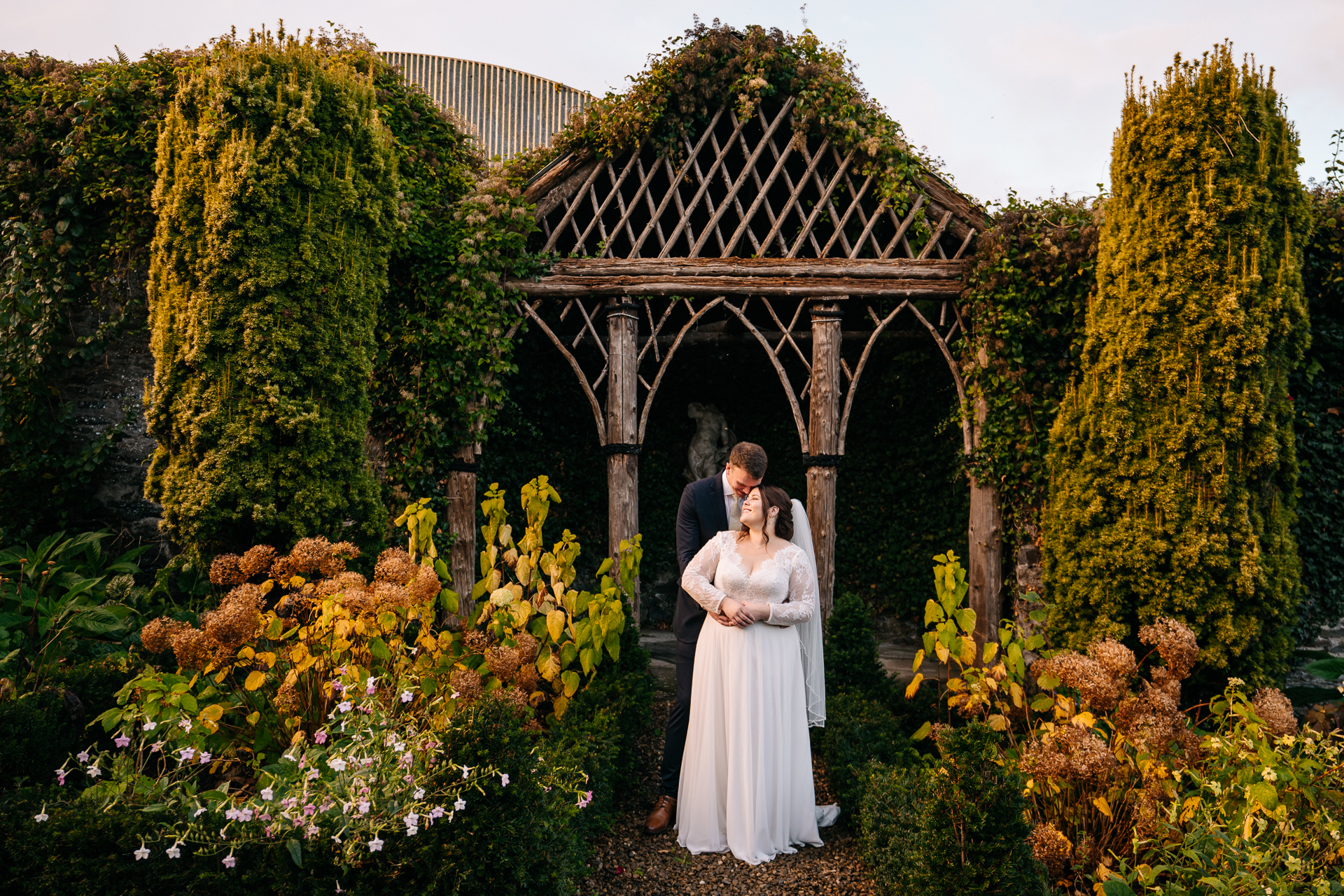 A man and woman posing in front of a garden of flowers