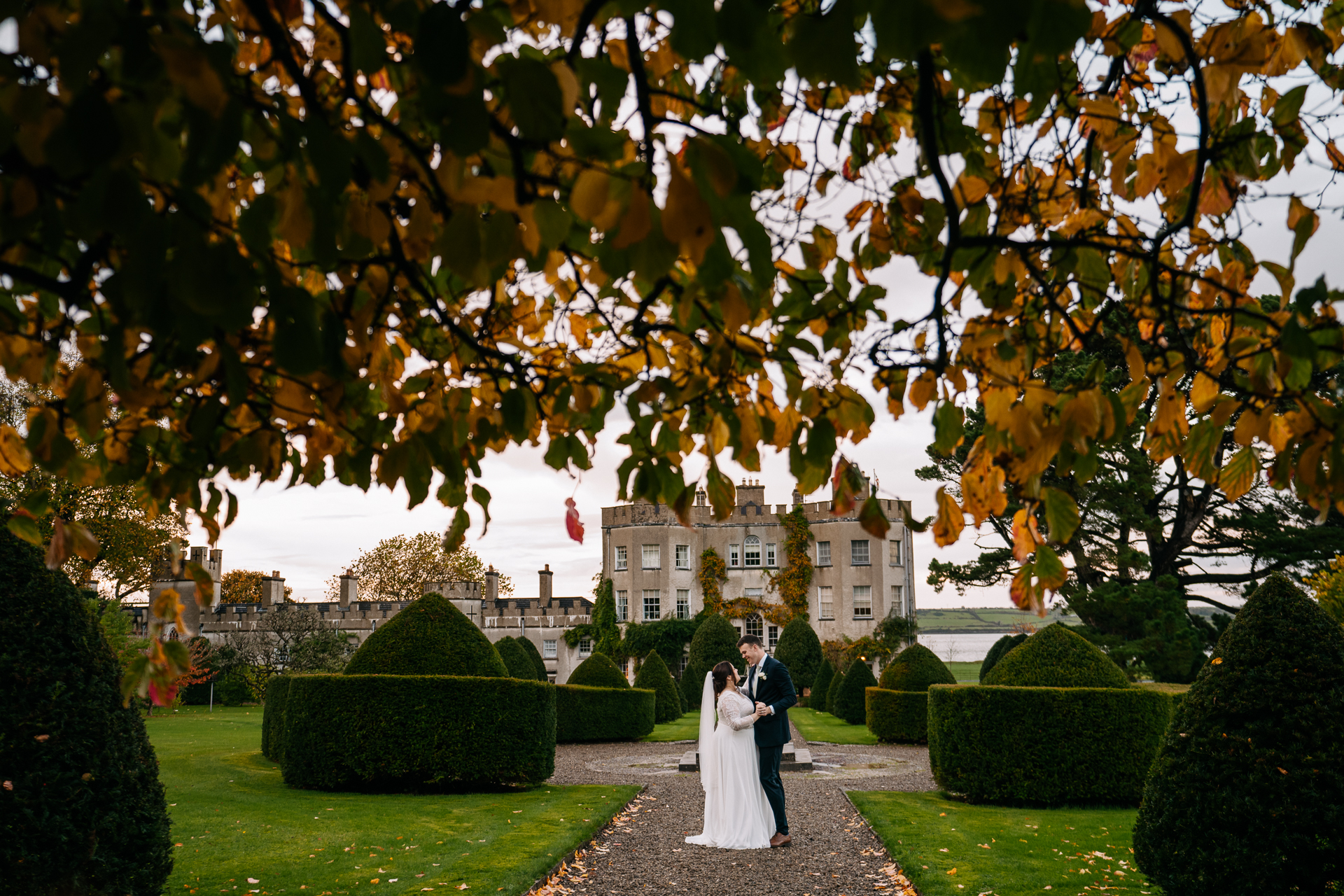 A man and woman in wedding attire kissing in a garden