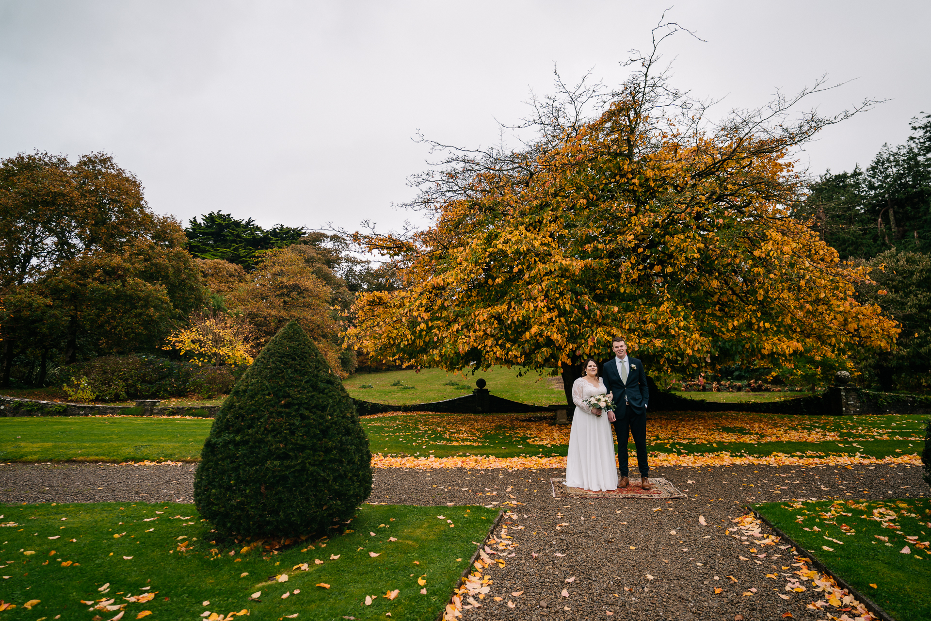 A man and woman in wedding attire standing in front of a tree