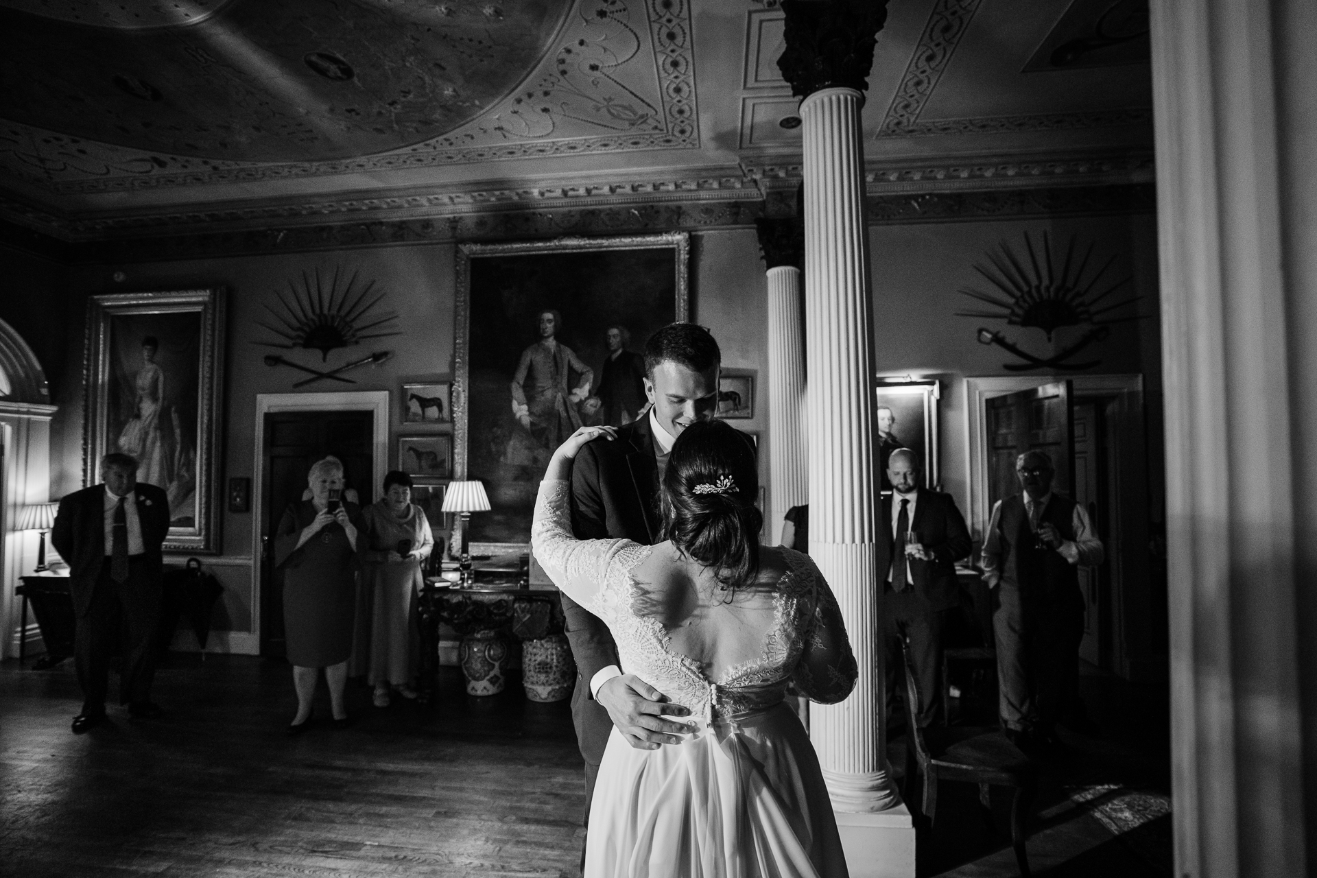 A man and woman dancing in a room with people in the background