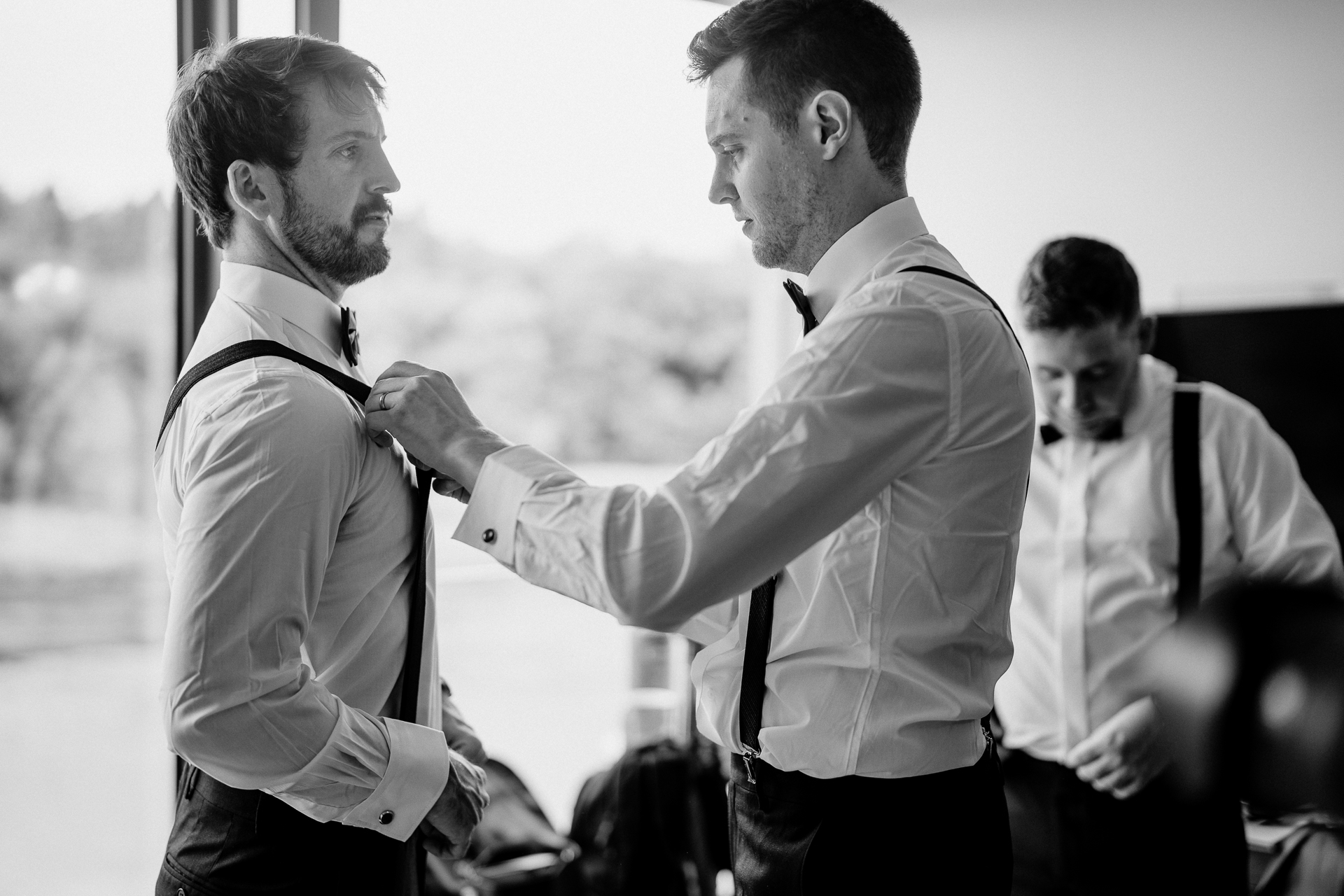 A man adjusting another man's tie