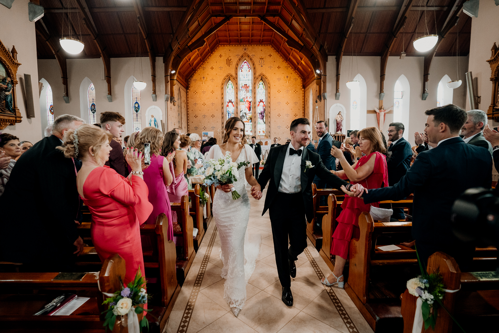 A man and woman walking down a aisle with a group of people