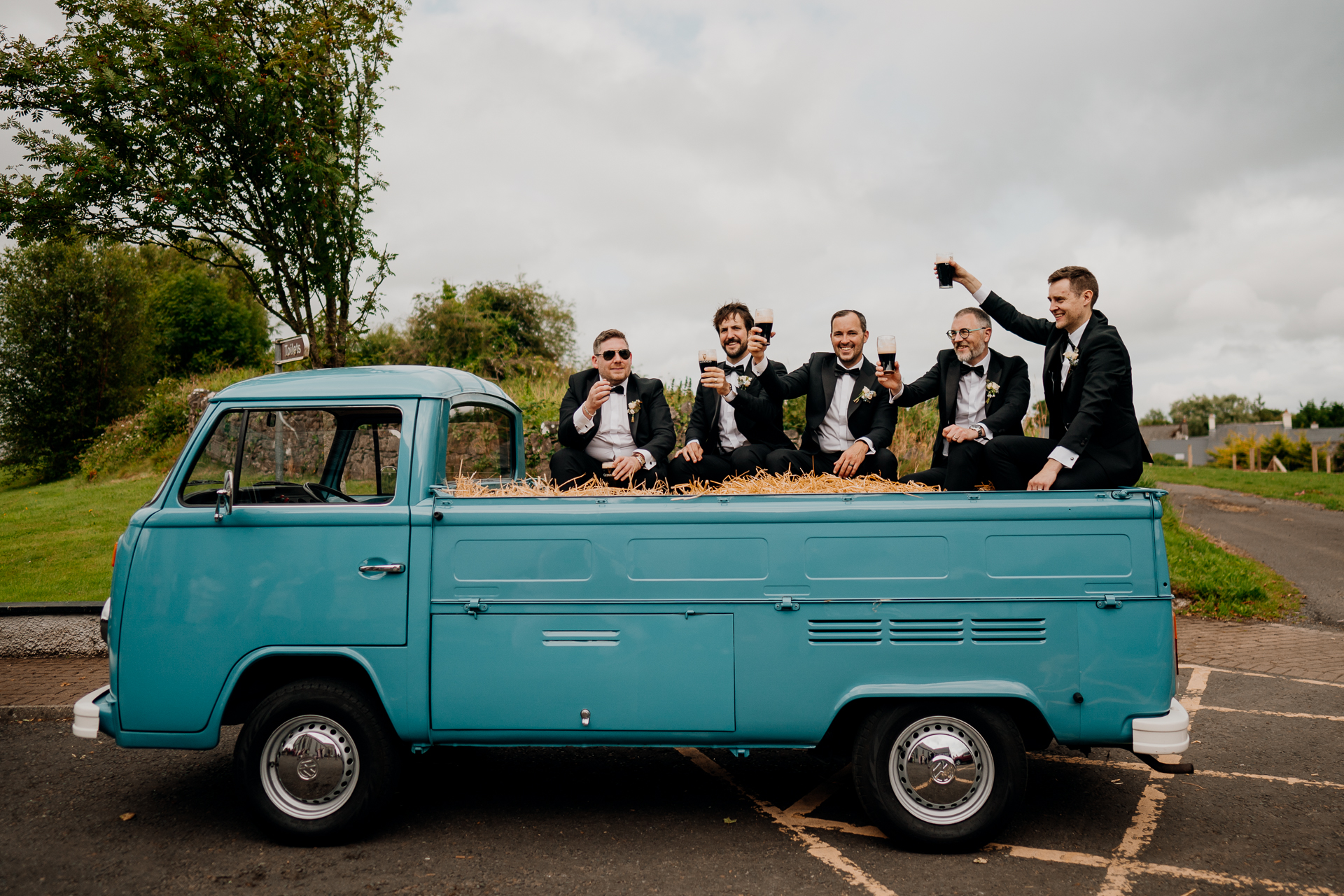 A group of men in suits standing on the back of a blue pickup truck