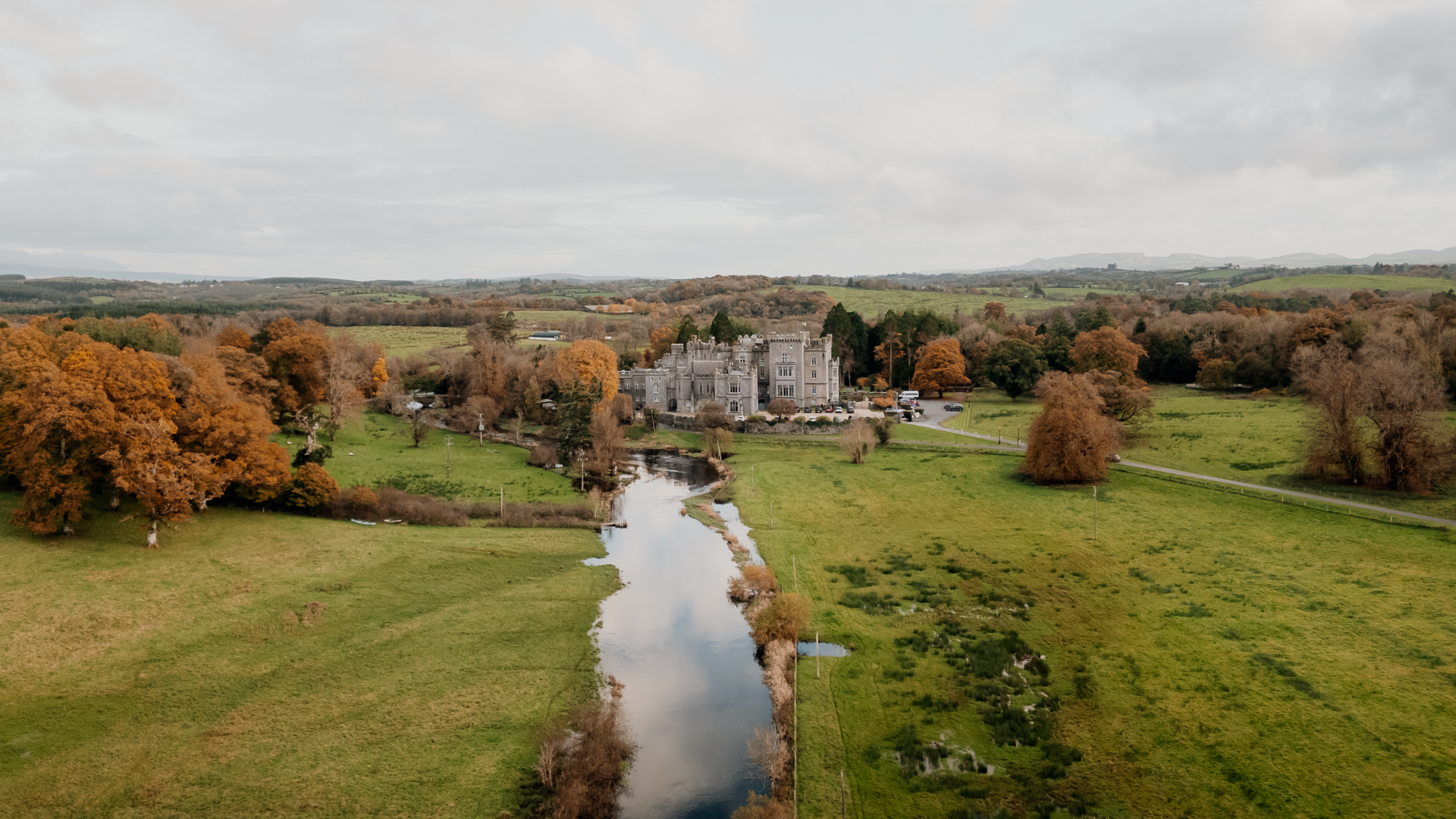 A river running through a grassy area with trees and a building in the background