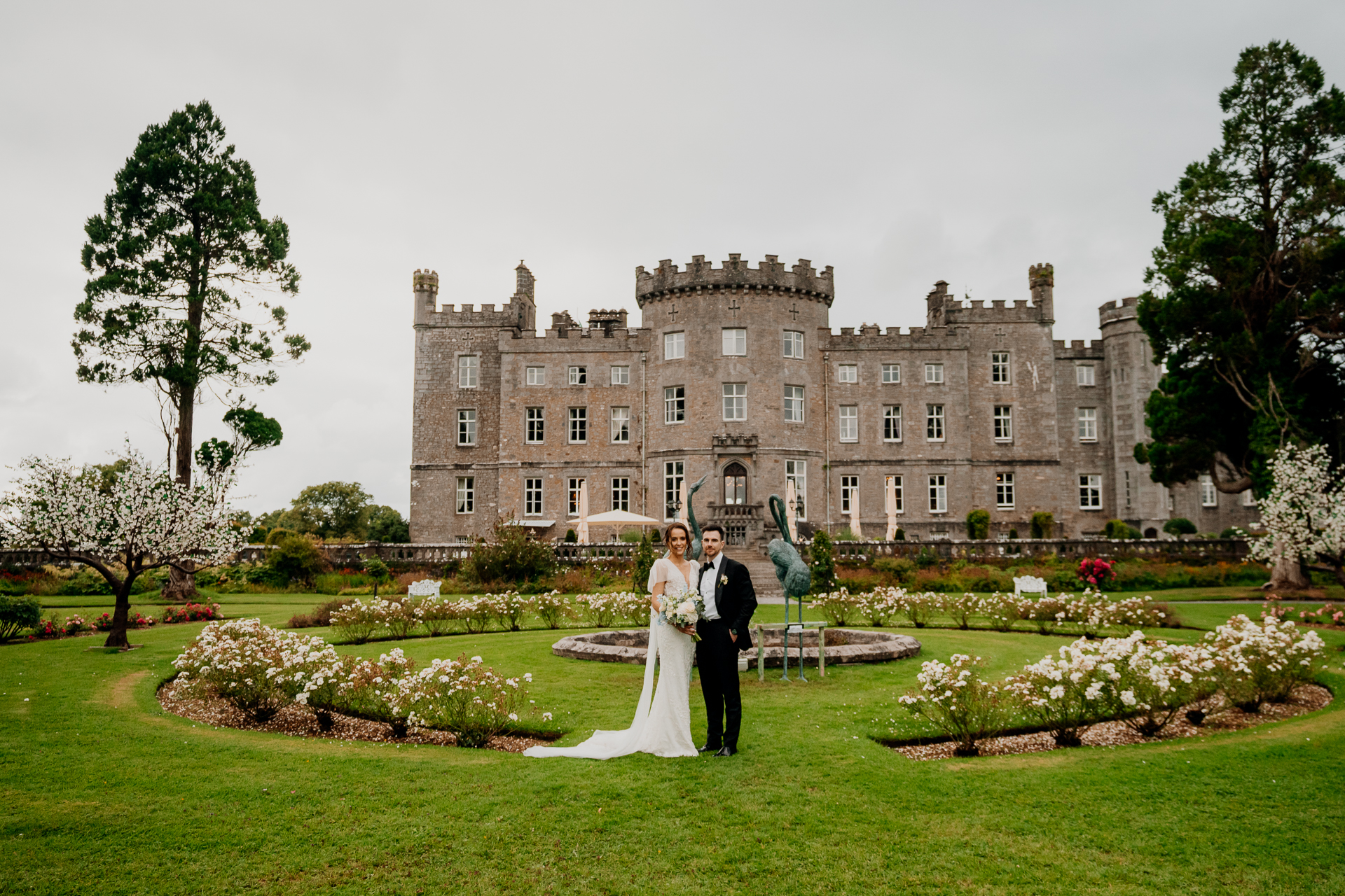 A man and woman in wedding attire in front of a large building