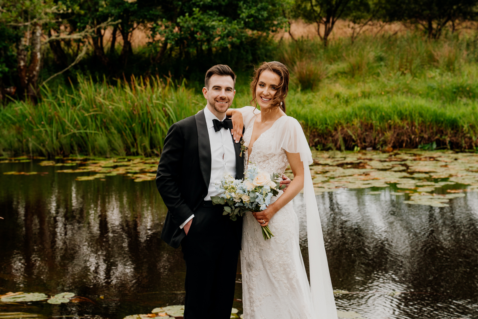 A man and woman posing for a picture next to a body of water