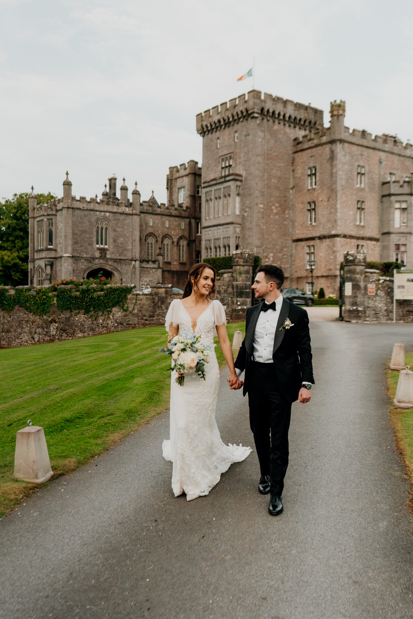 A man and woman walking down a road in front of a castle