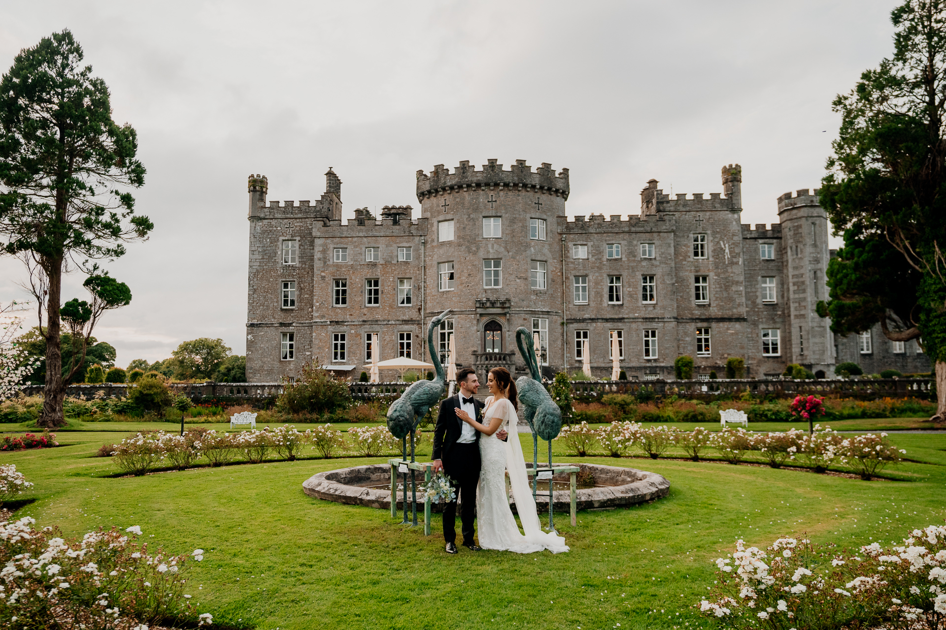 A man and woman posing in front of a large building