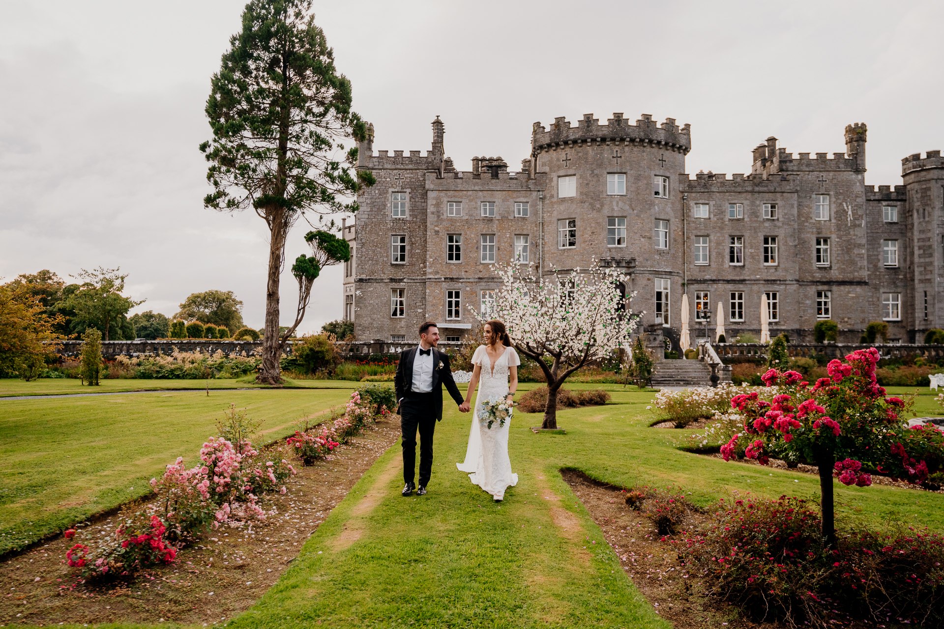 A man and woman posing in front of a large building