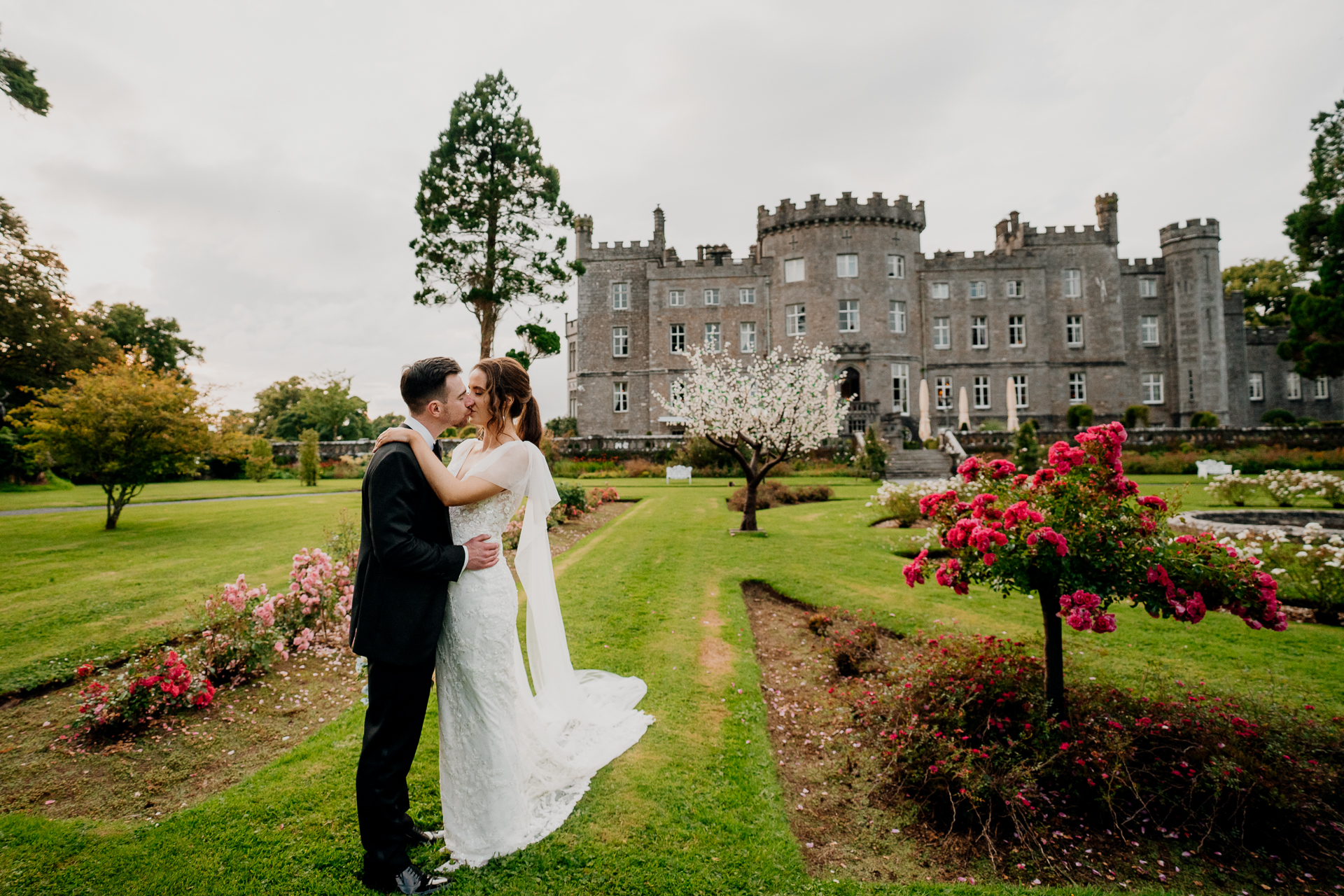 A man and woman kissing in front of a large building