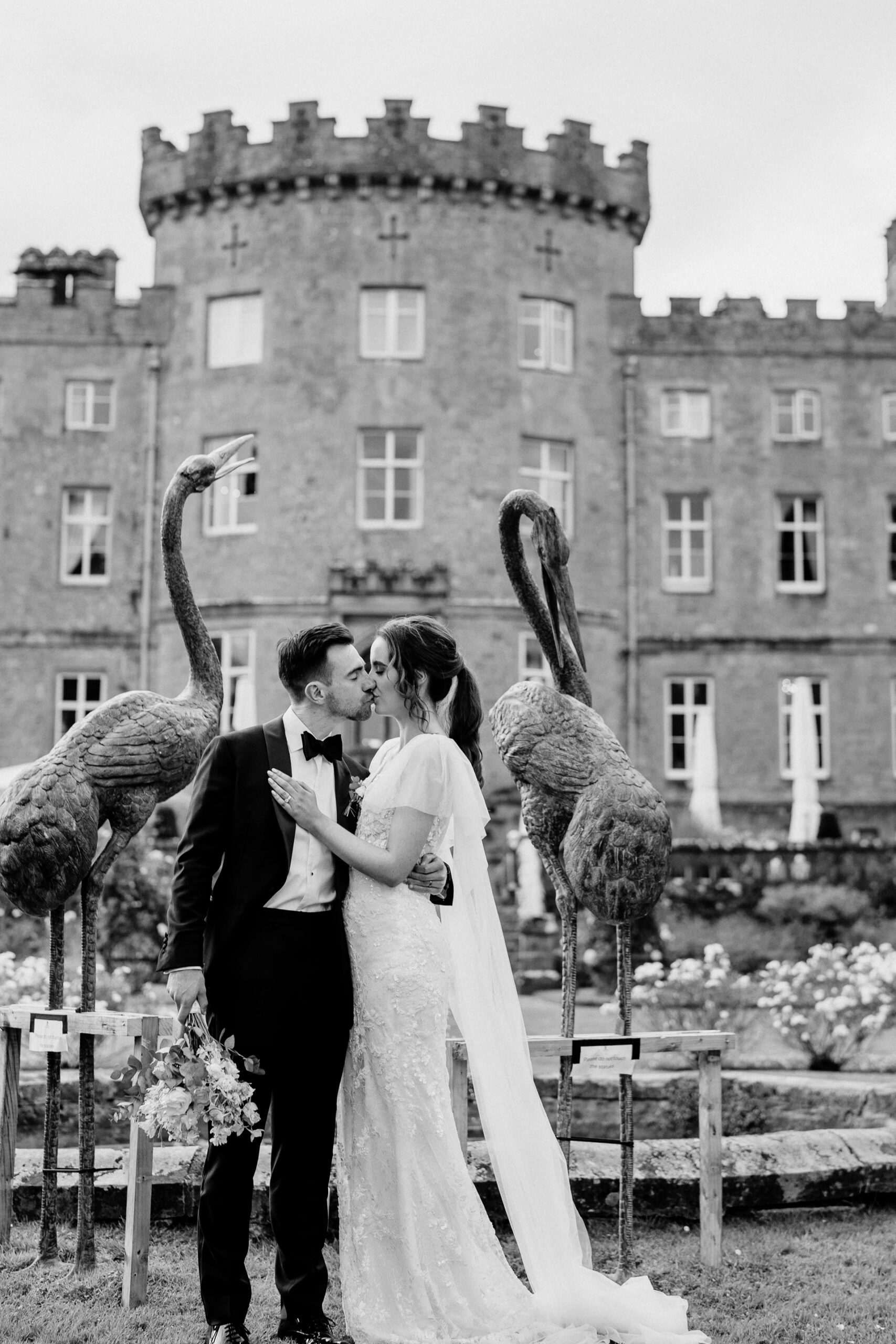 A man and woman kissing in front of a building with a large bird