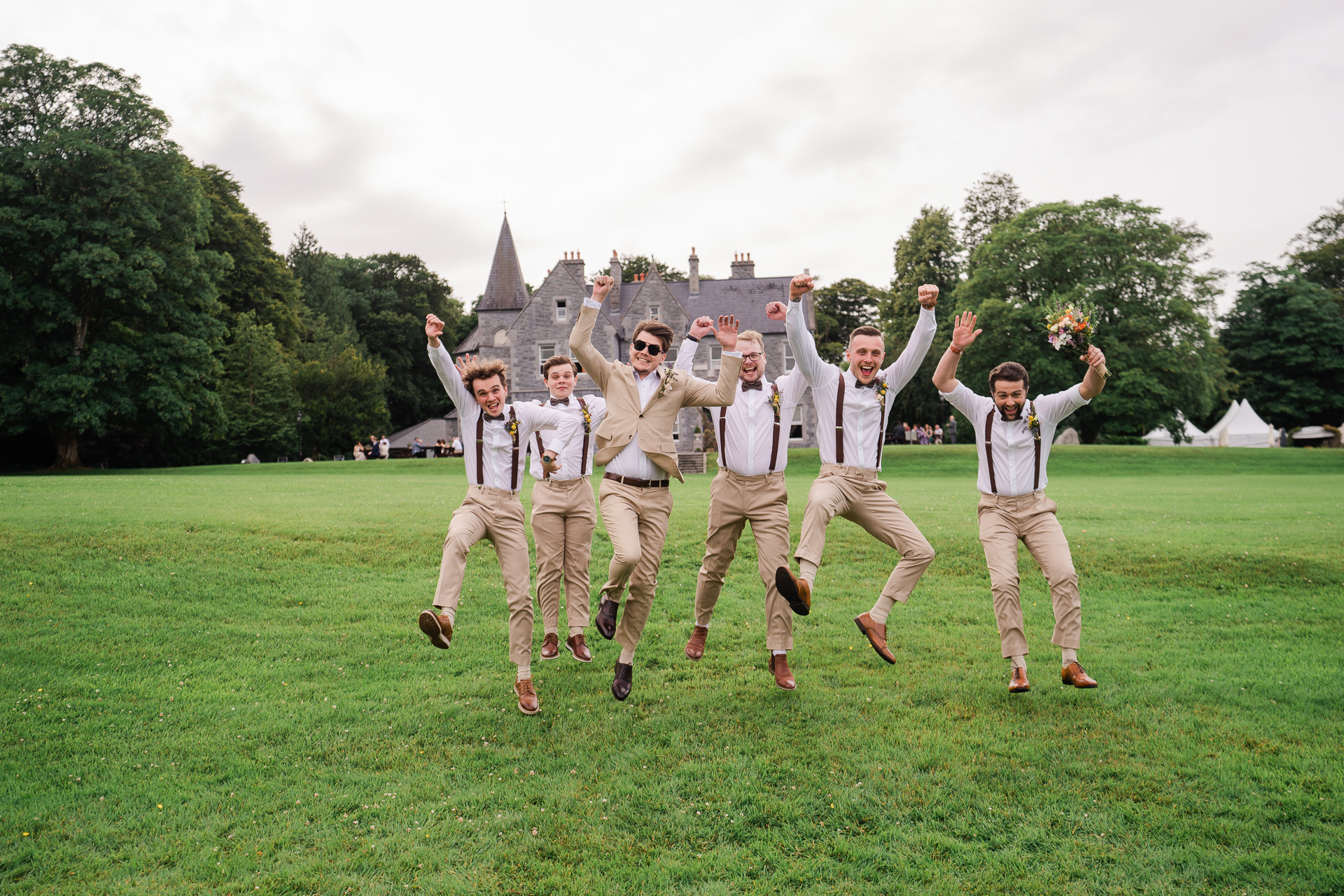 A group of men jumping in the air with Clos Lucé in the background