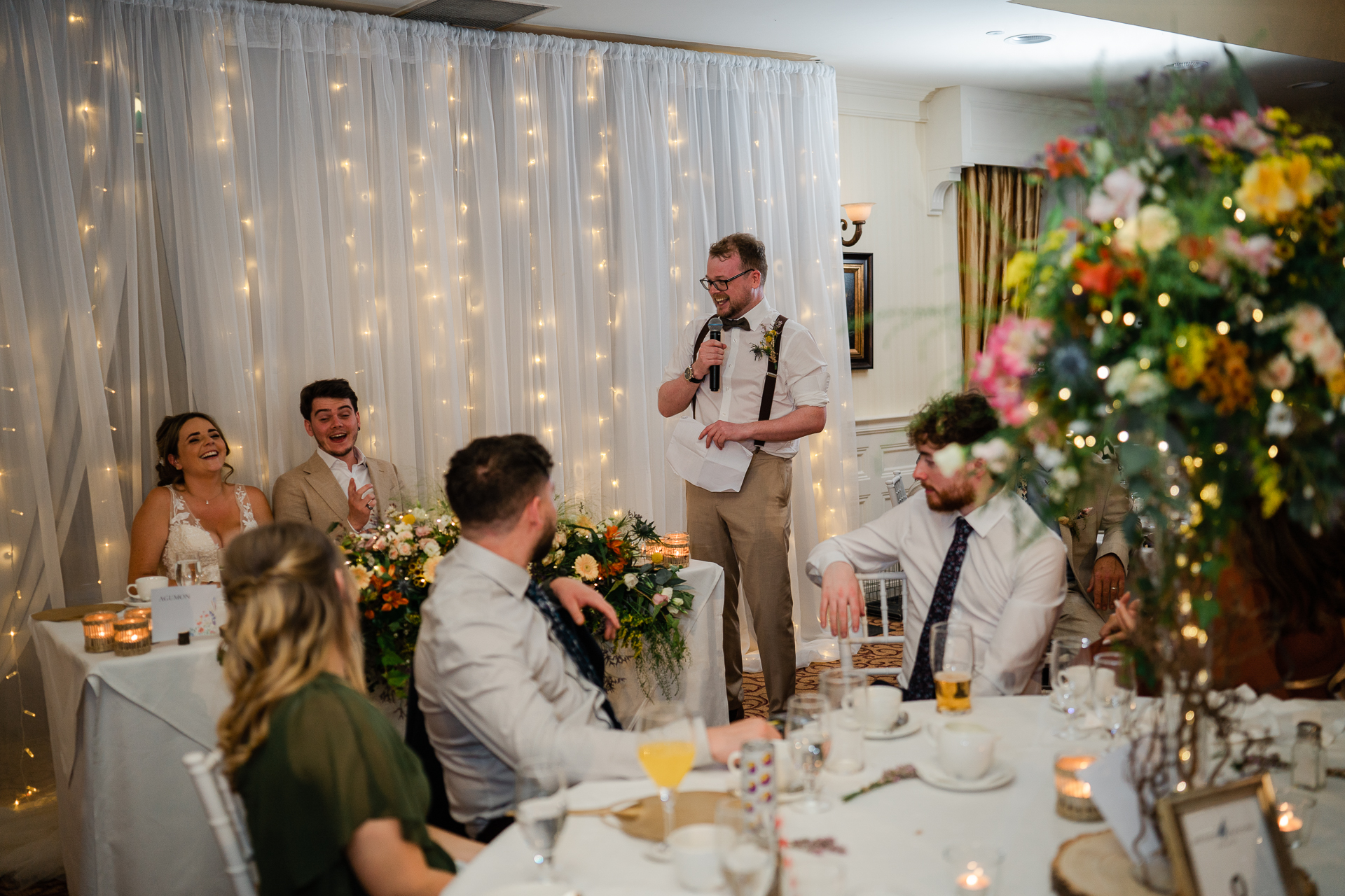 A person speaking to a group of people at a wedding reception