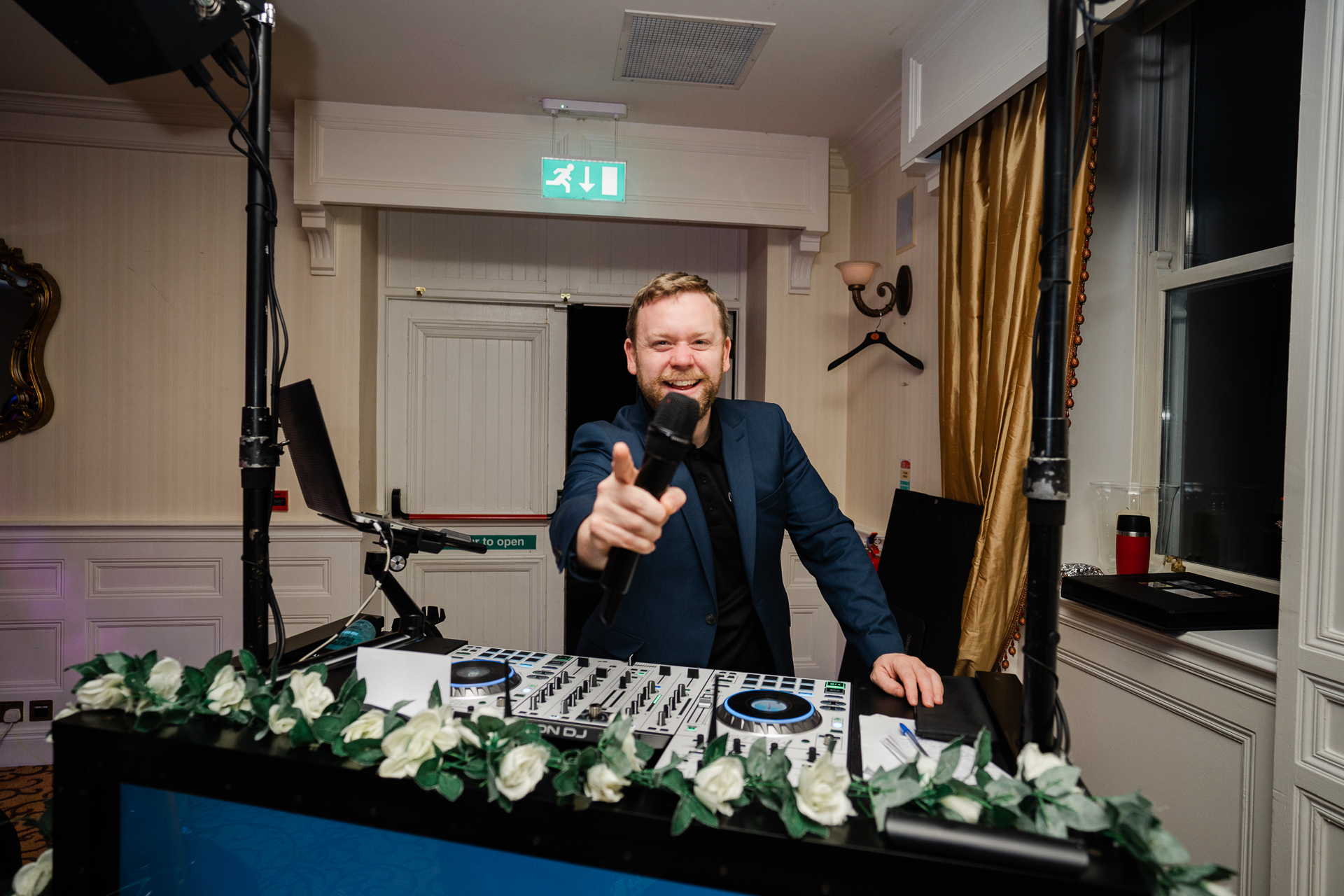 A person holding a microphone and standing behind a table with flowers