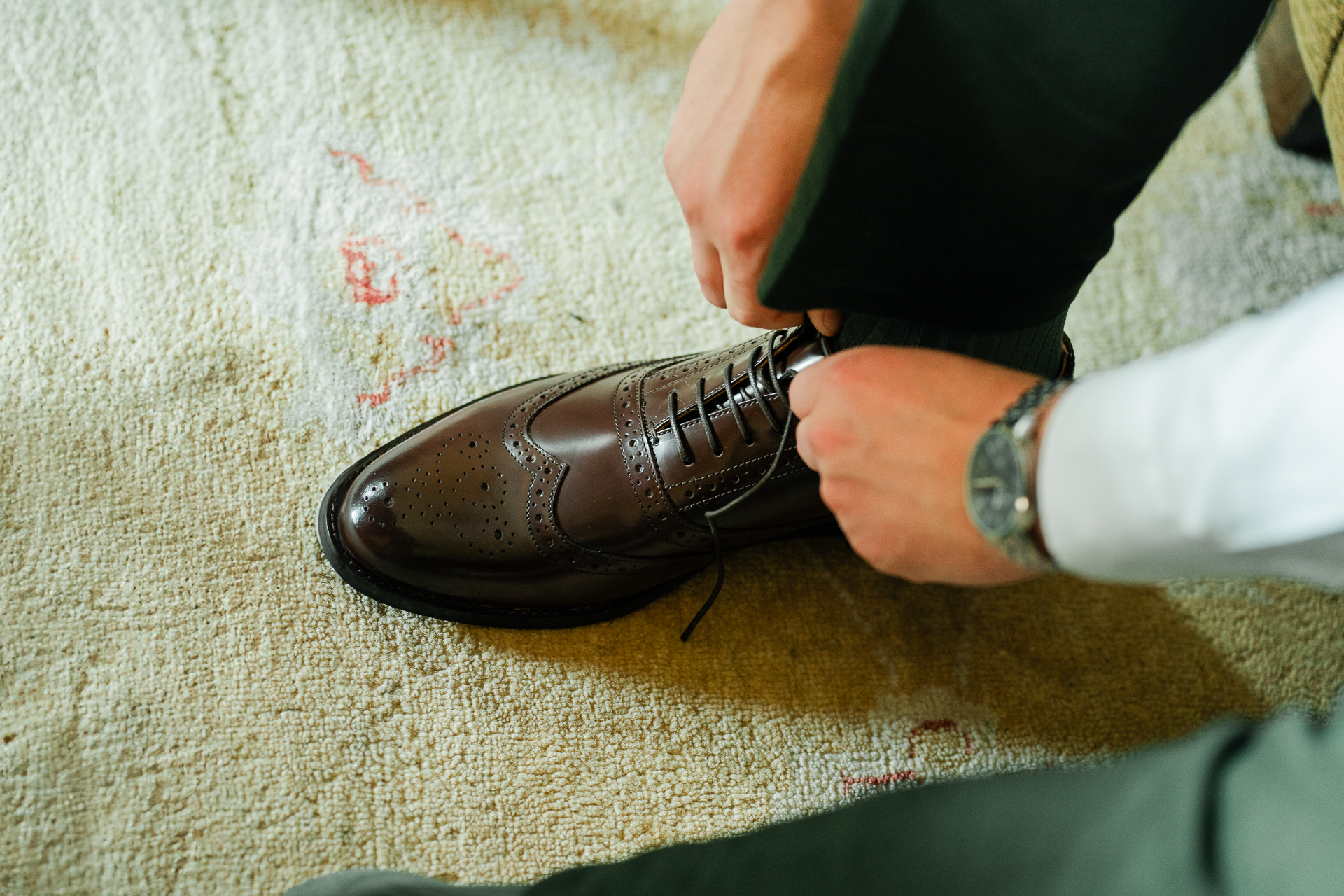 A person's hand holding a brown leather shoe