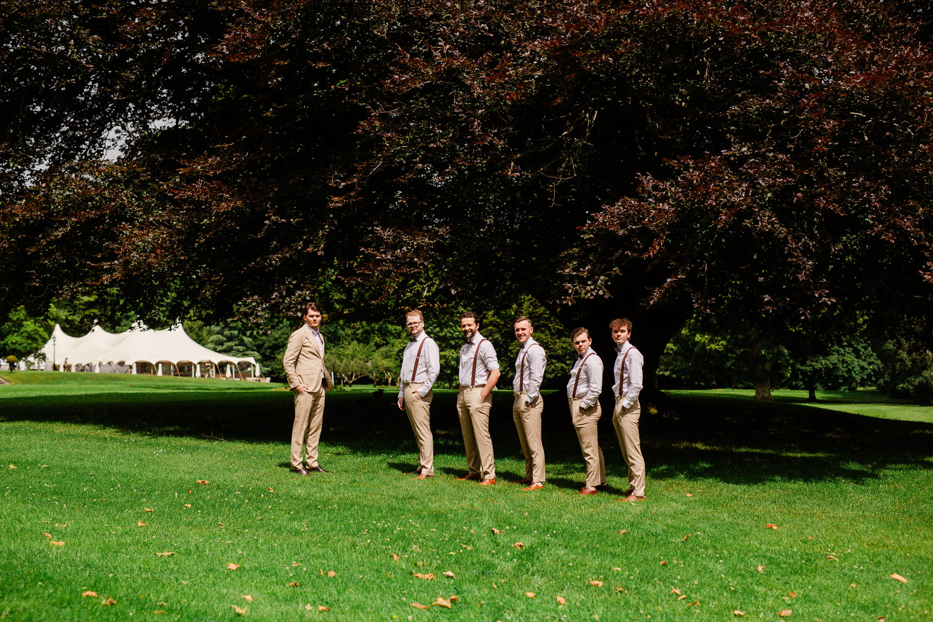 A group of men standing in a grassy area with trees in the background