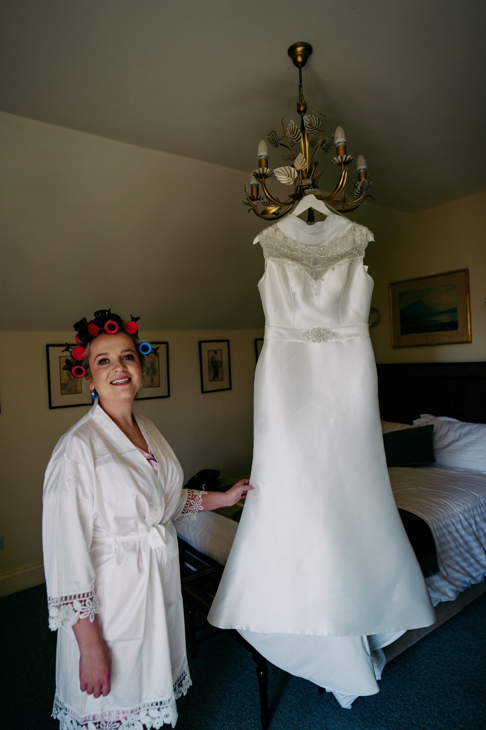 A person in a white dress and a crown standing next to a personnequin in a room