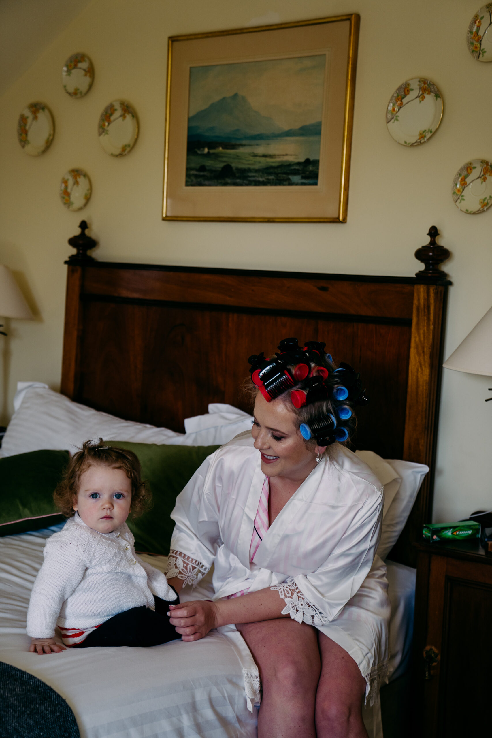 A person and a baby sitting on a bed