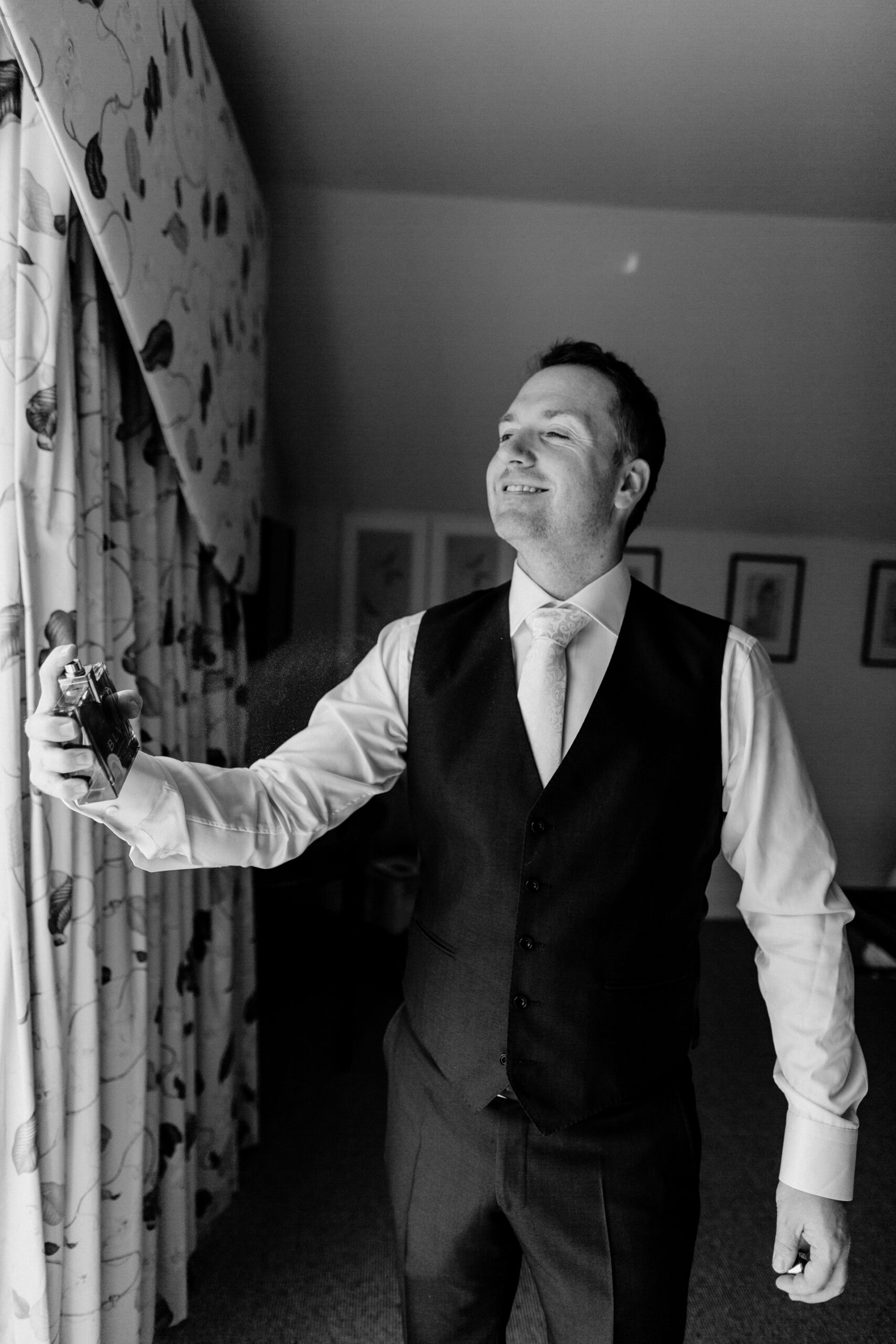 A man in a suit holding a bottle of alcohol