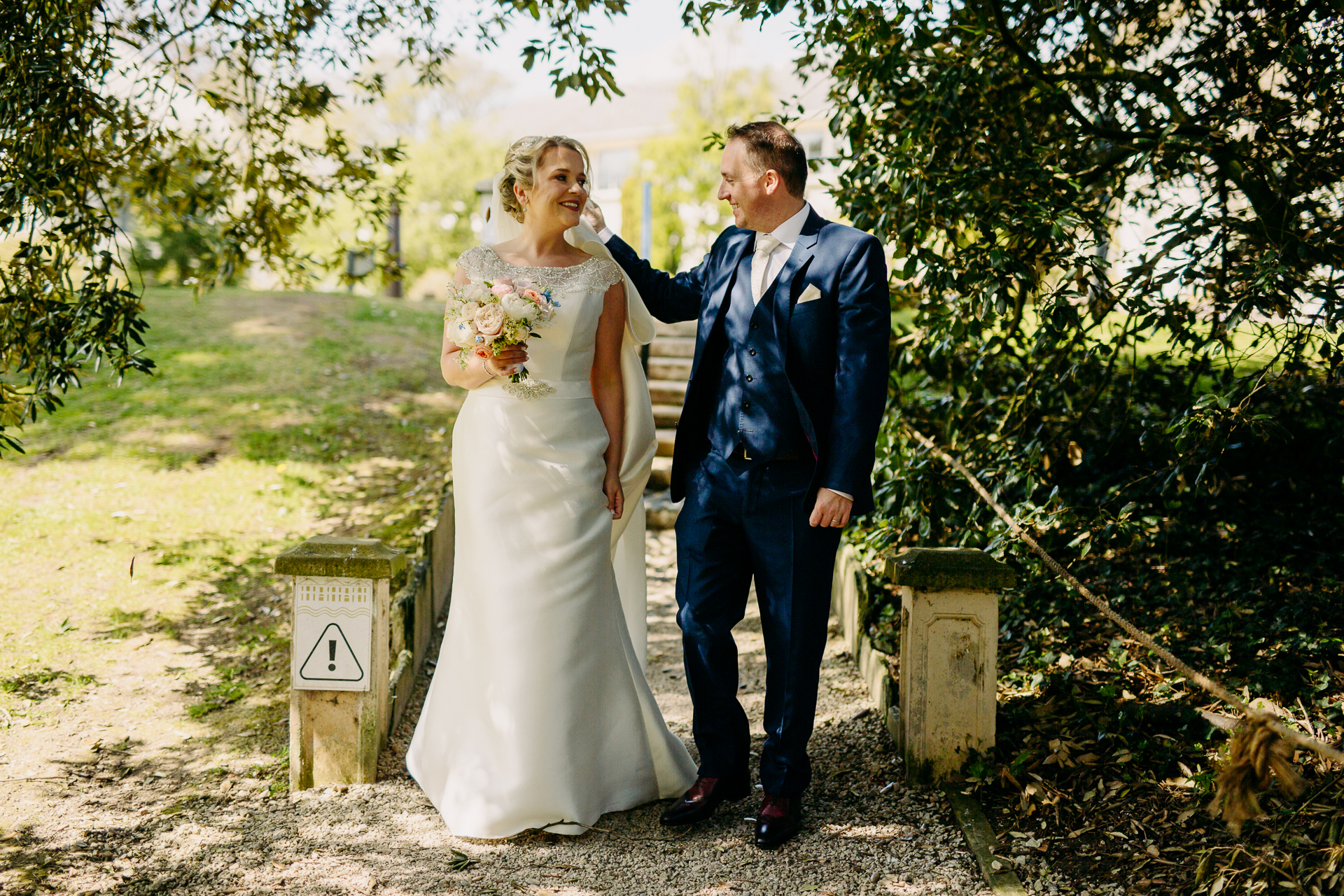 A man and woman walking down a path with a gravestone and a tree