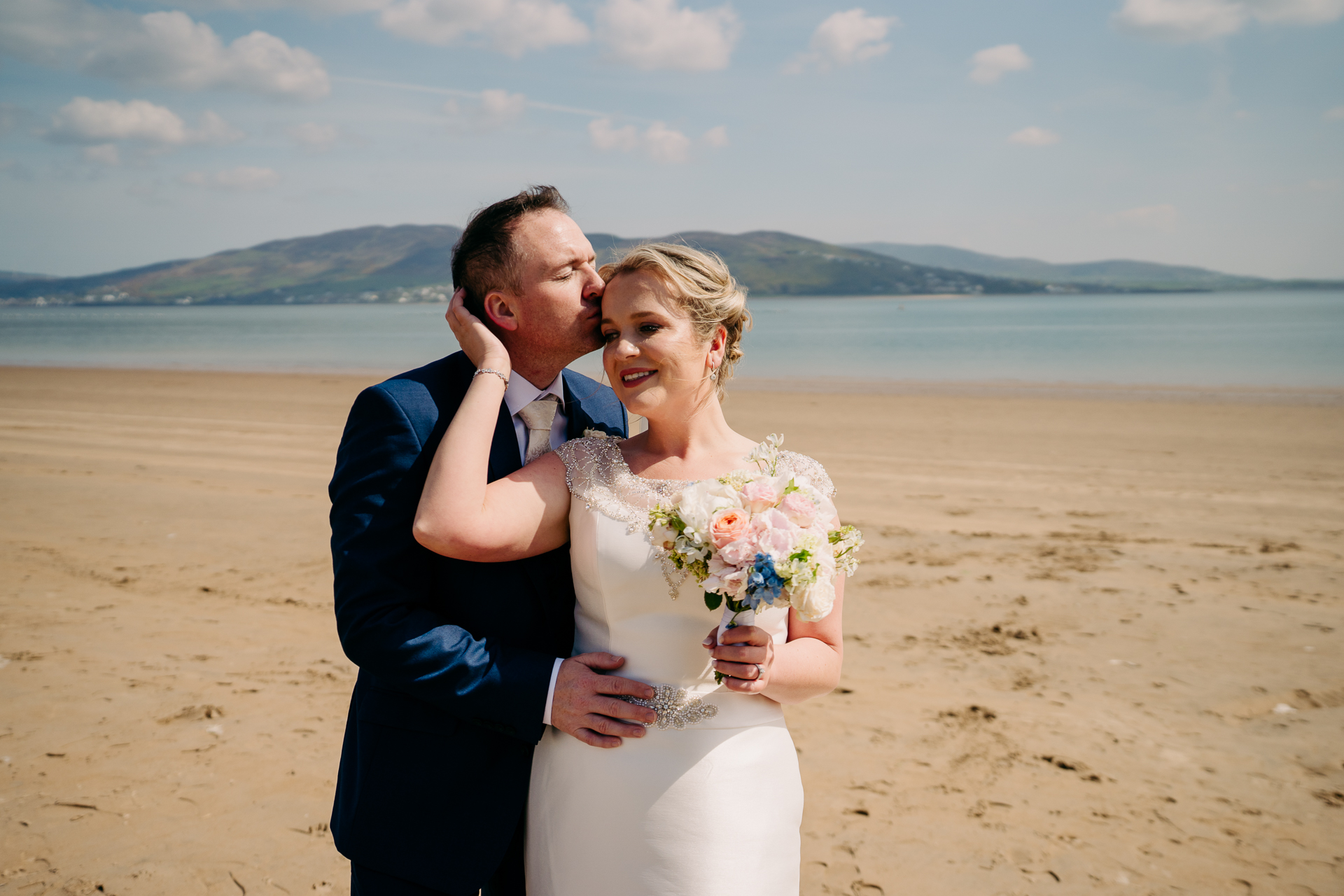 A man and woman kissing on a beach